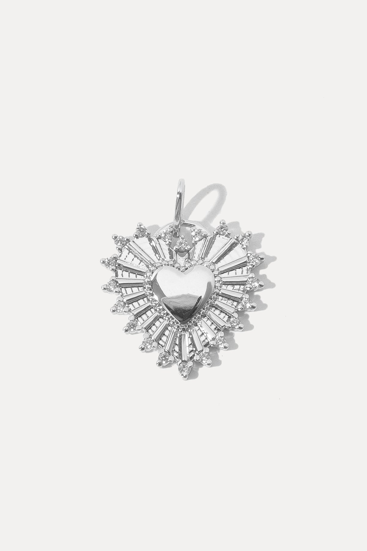 Silver heart-shaped Adorn Charm with sunburst rays and CZ border flat lay on a white background.