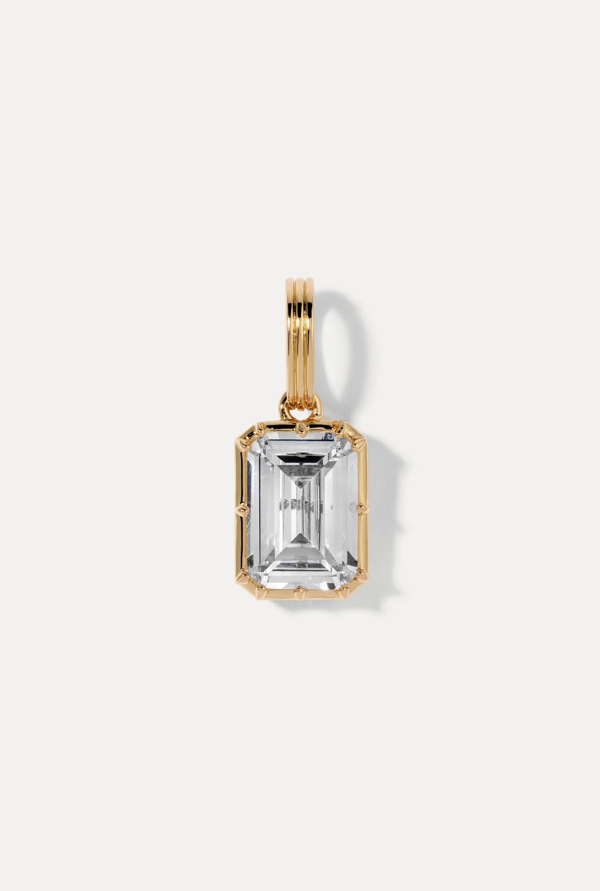 Gold emerald-cut Allure Charm set in sleek sculptural casing flat lay on a white background.