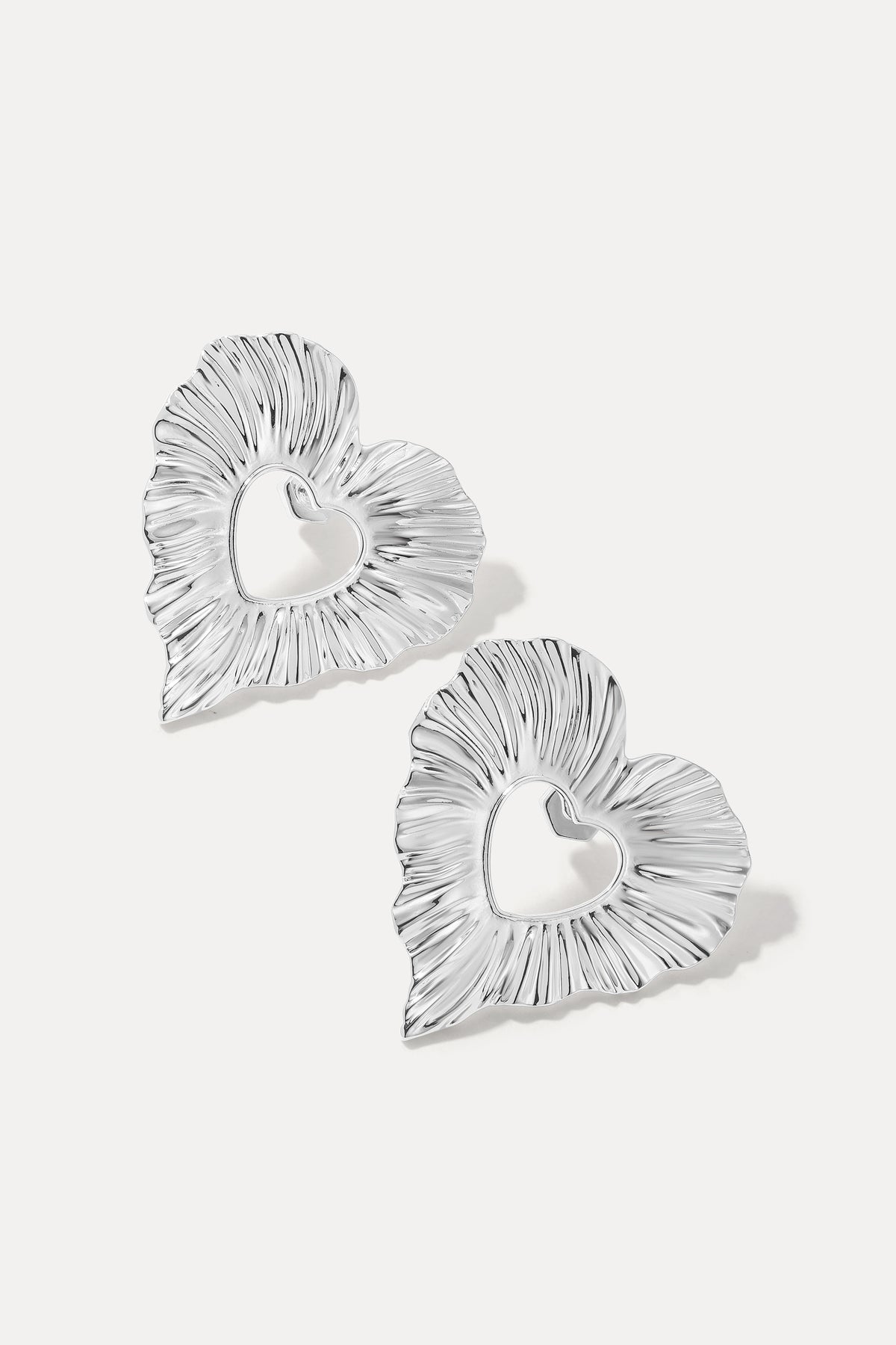 Pair of silver Amour textured heart statement earrings on a white background.