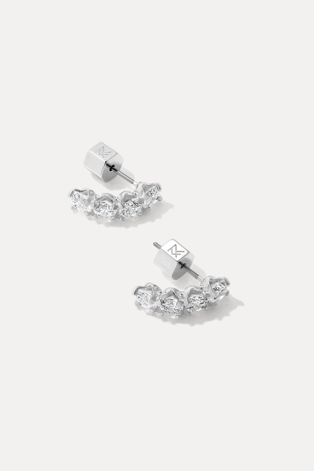 Pair of silver Ansley curved stud earrings set with round cubic zirconias on a plain background.