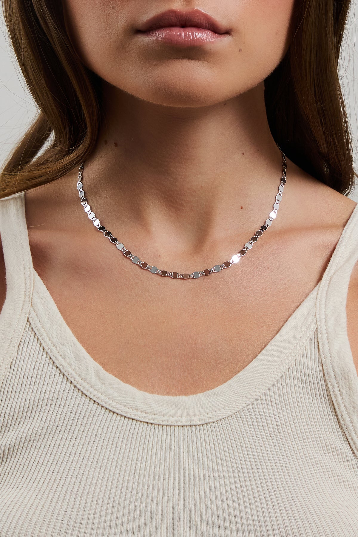 Model wearing silver Ava mirror chain necklace, styled with a cream ribbed tank top.
