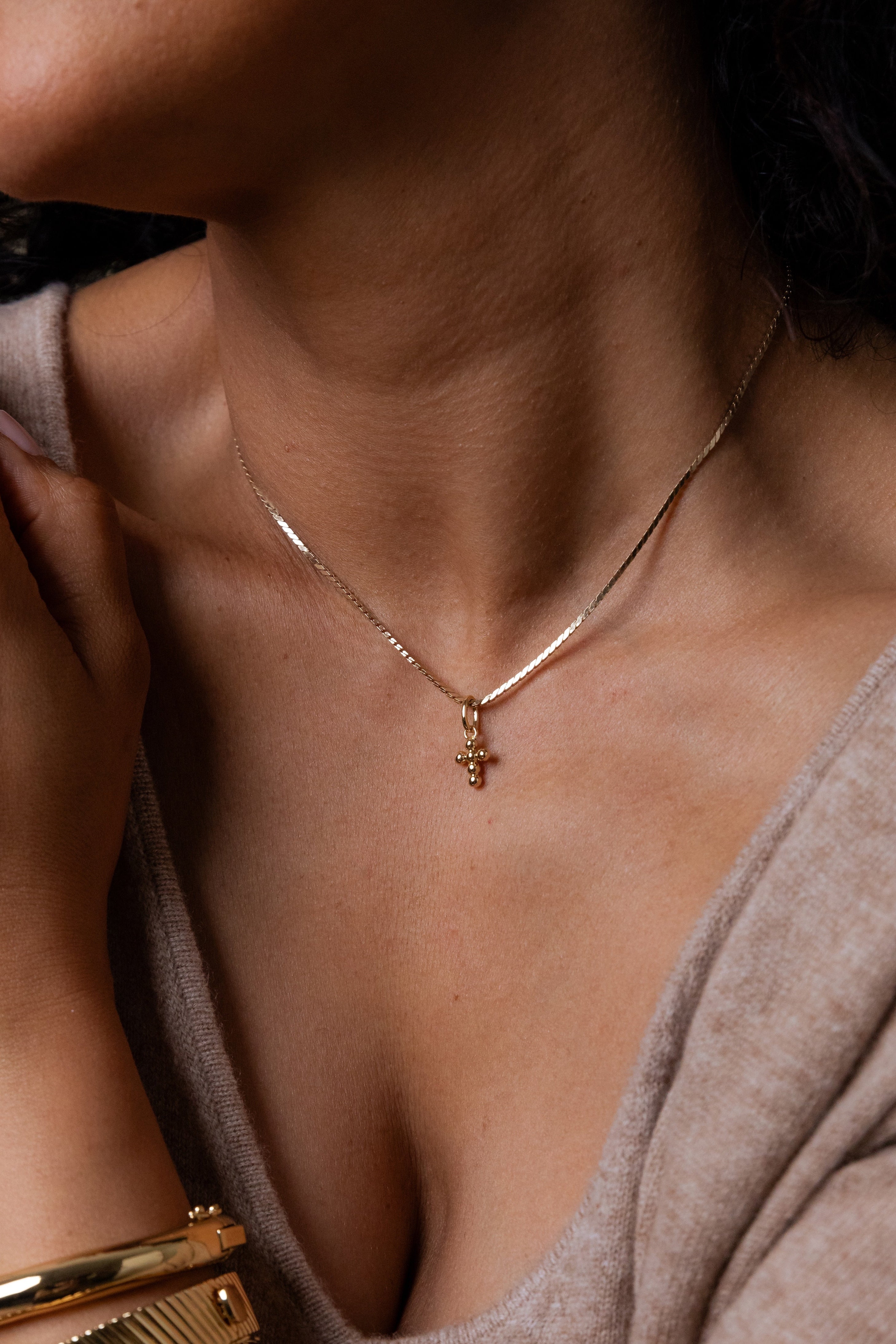 Close-up of a person wearing a gold necklace with a small pendant.
