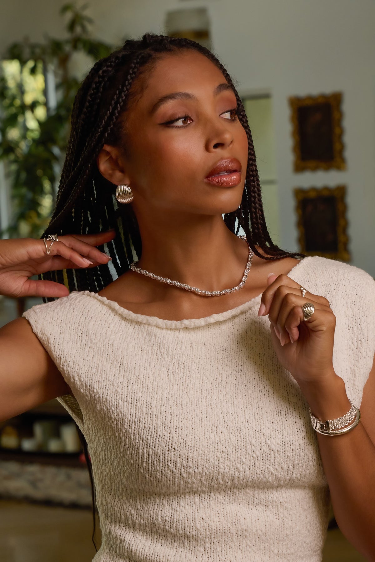 Model wearing silver Delilah tennis necklace, Florence dome earrings, and rings styled in a cream textured knit top.