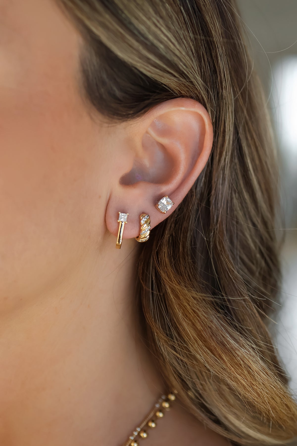 Model wearing the gold Dahlia Huggies in an earring stack.