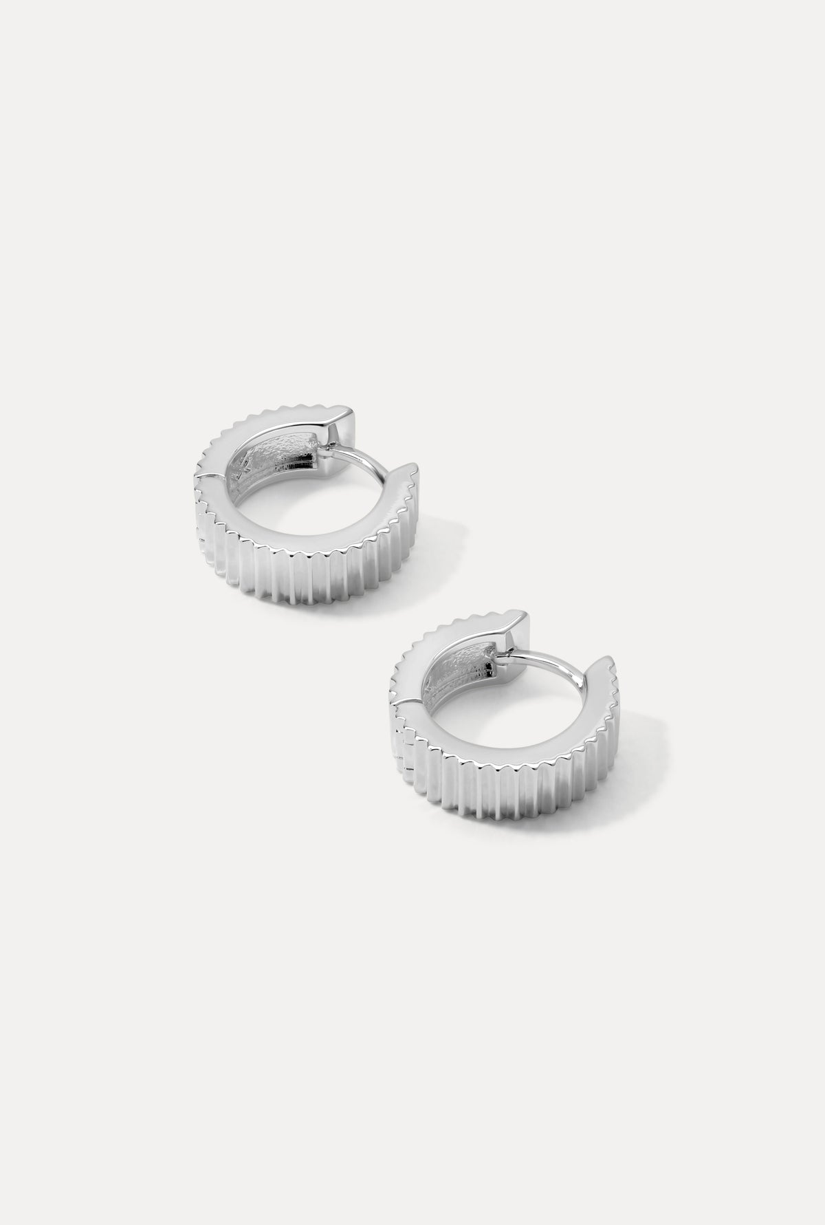 Silver Debbie huggie hoop earrings with bold ridged texture on a plain white background.