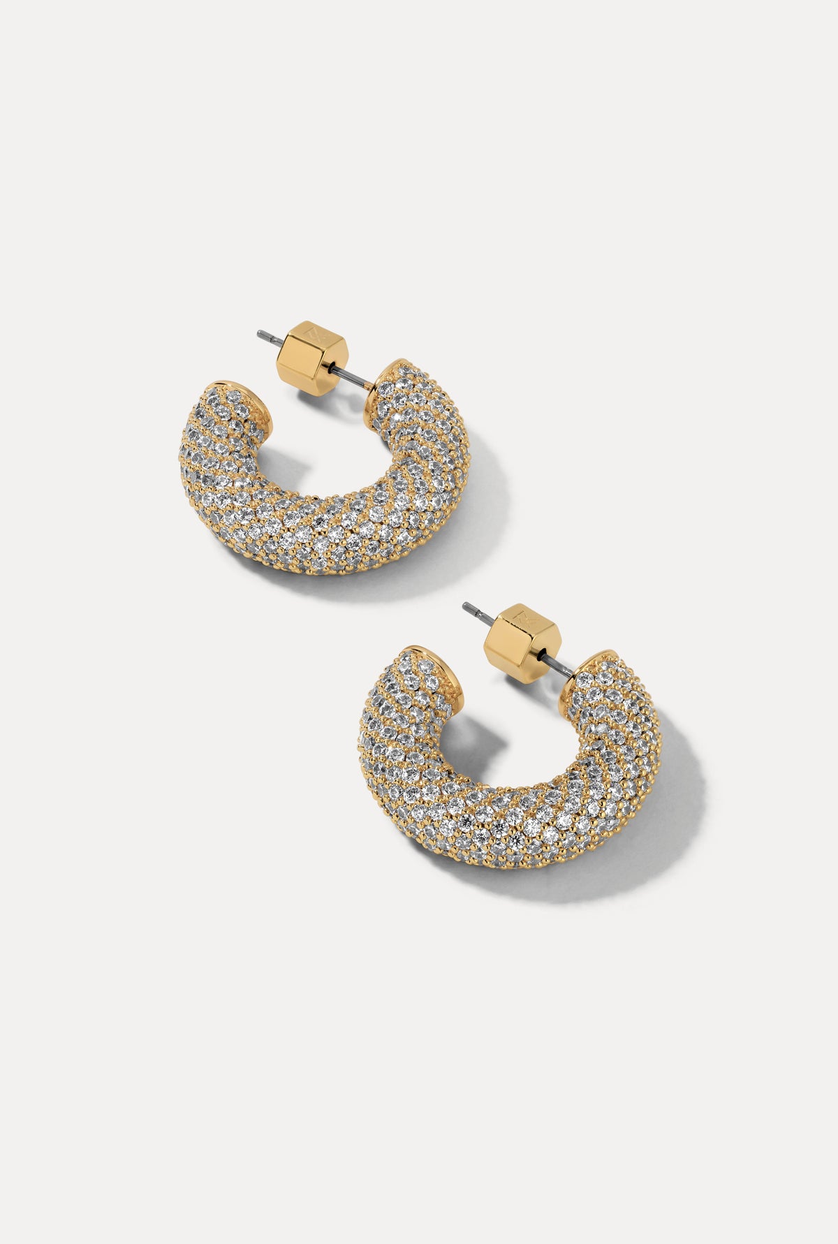 Gold thick rounded hoop earrings with full cubic zirconia pavé detailing on a plain white background.