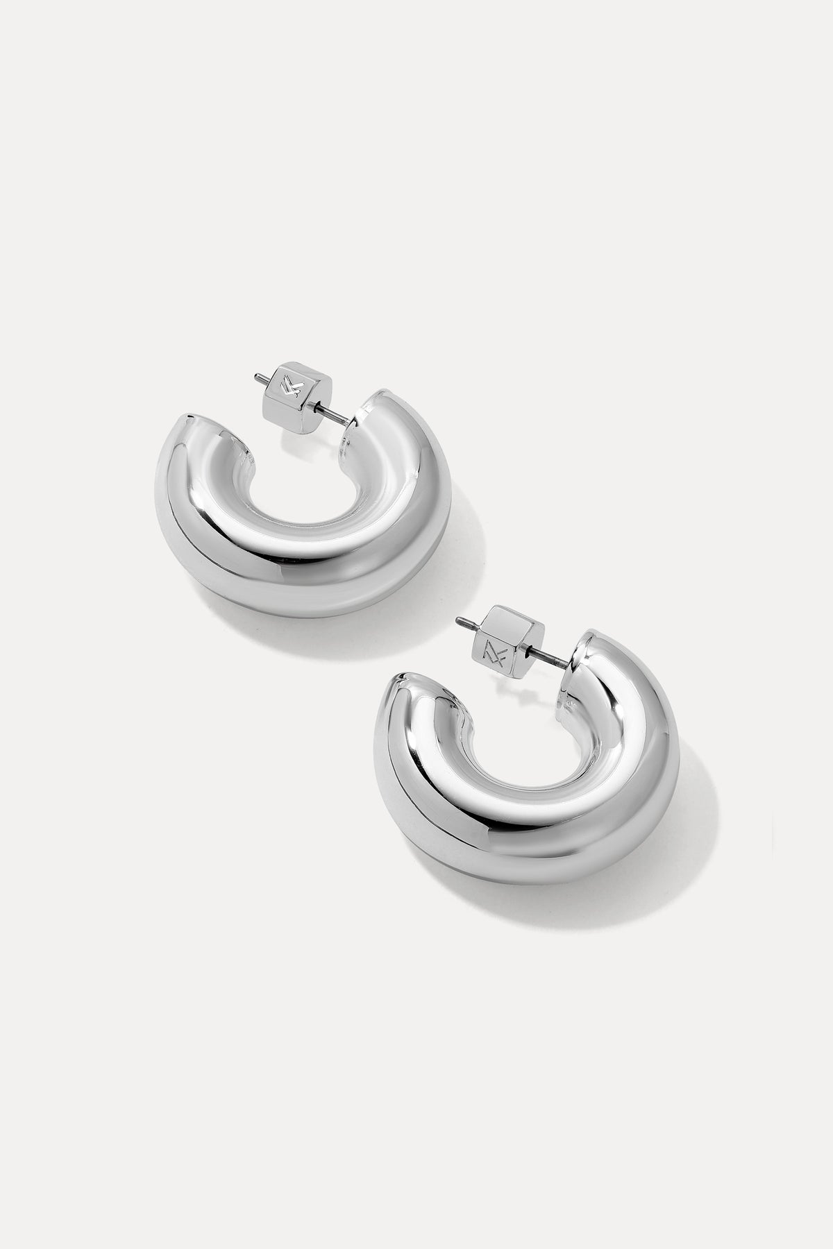 Silver thick rounded Drew huggie hoop earrings displayed on a plain white background.