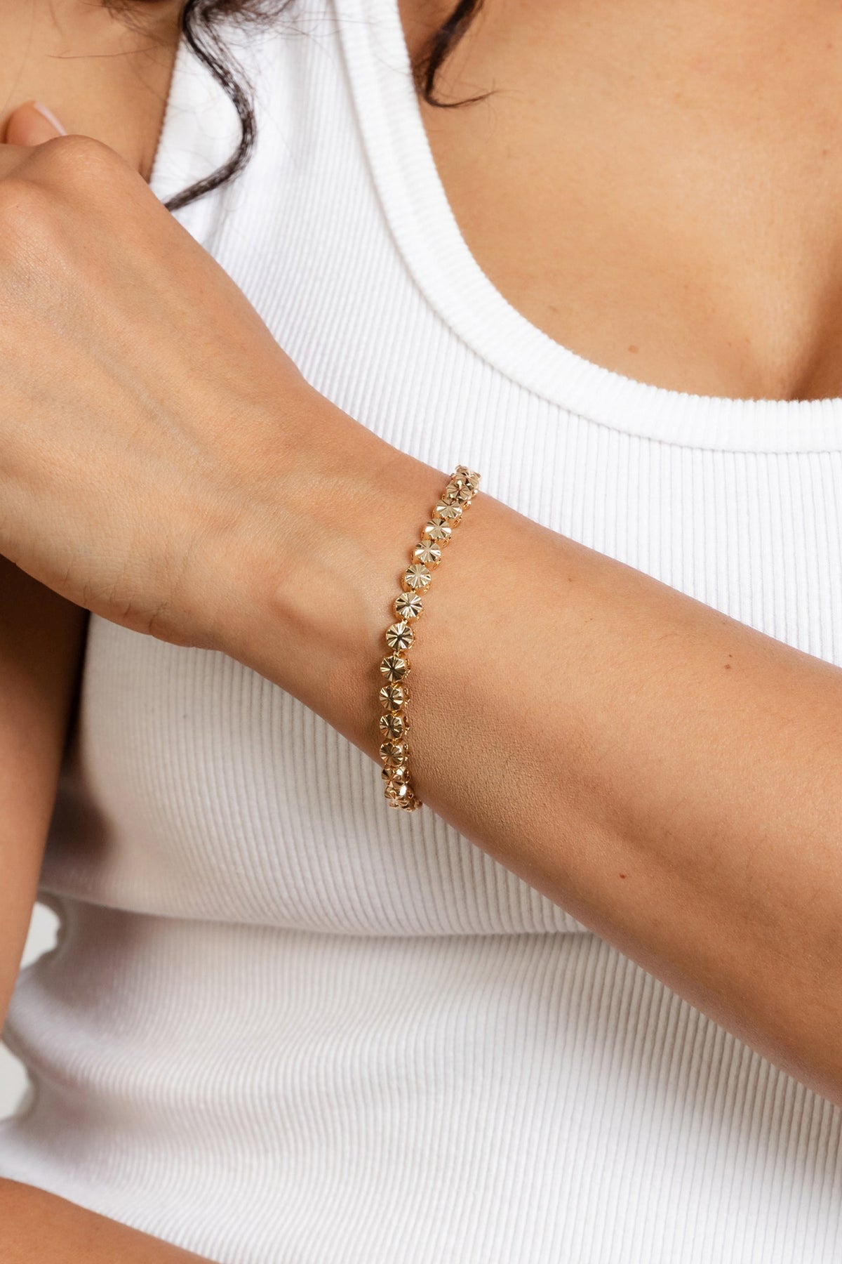 Model wearing the gold Essie bracelet solo on the wrist against a white tank top