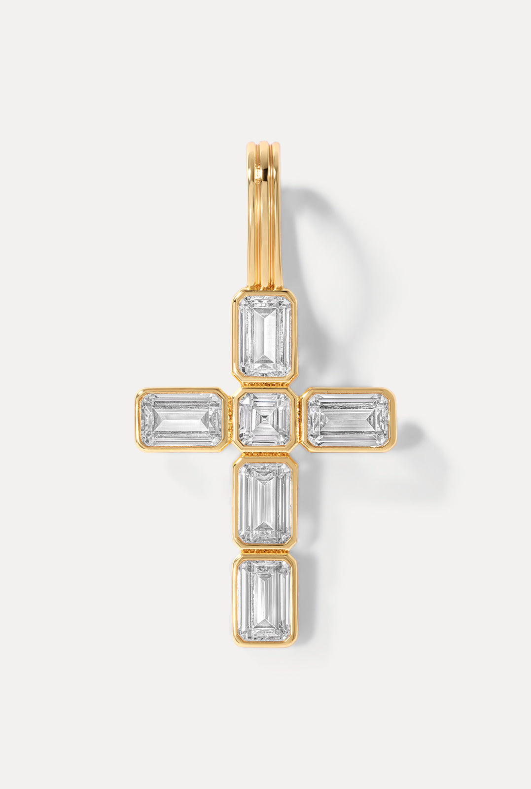 Diamond cross pendant in gold showcasing it's emerald cut CZ's on a white background.