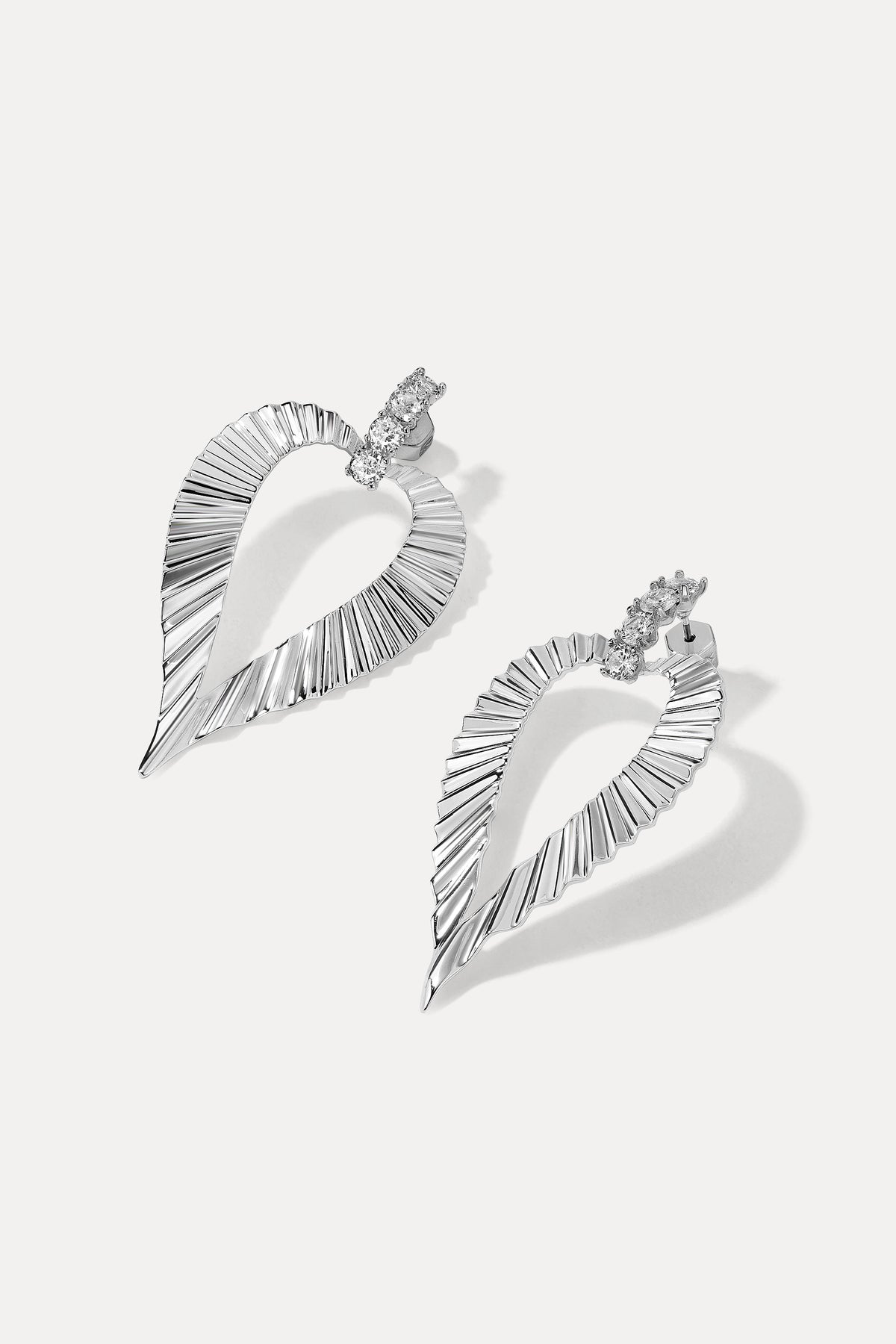 Pair of silver Jasmine Earrings with crystal studs and ribbed heart drop on white.
