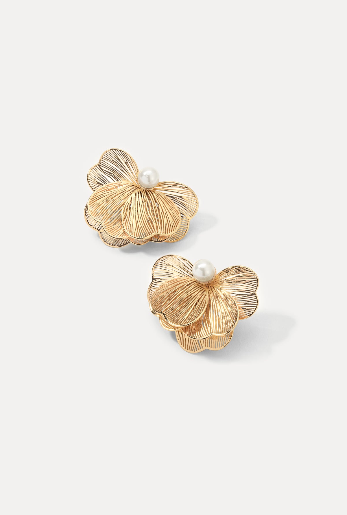 Pair of gold Lily Earrings featuring textured petal design with pearl centers on white.