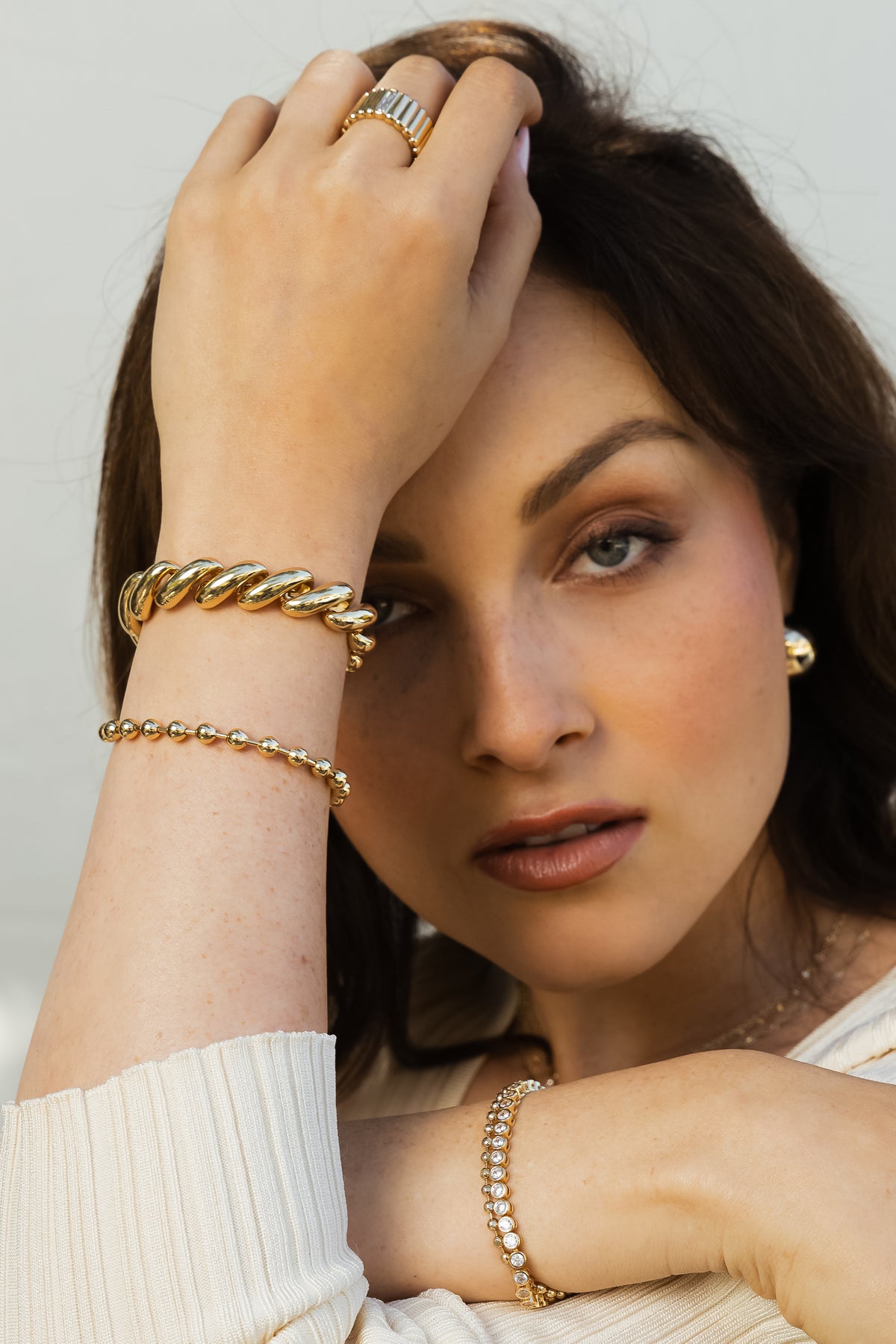 Close-up model image of the gold Paige and Kelsey bracelets being stacked together.