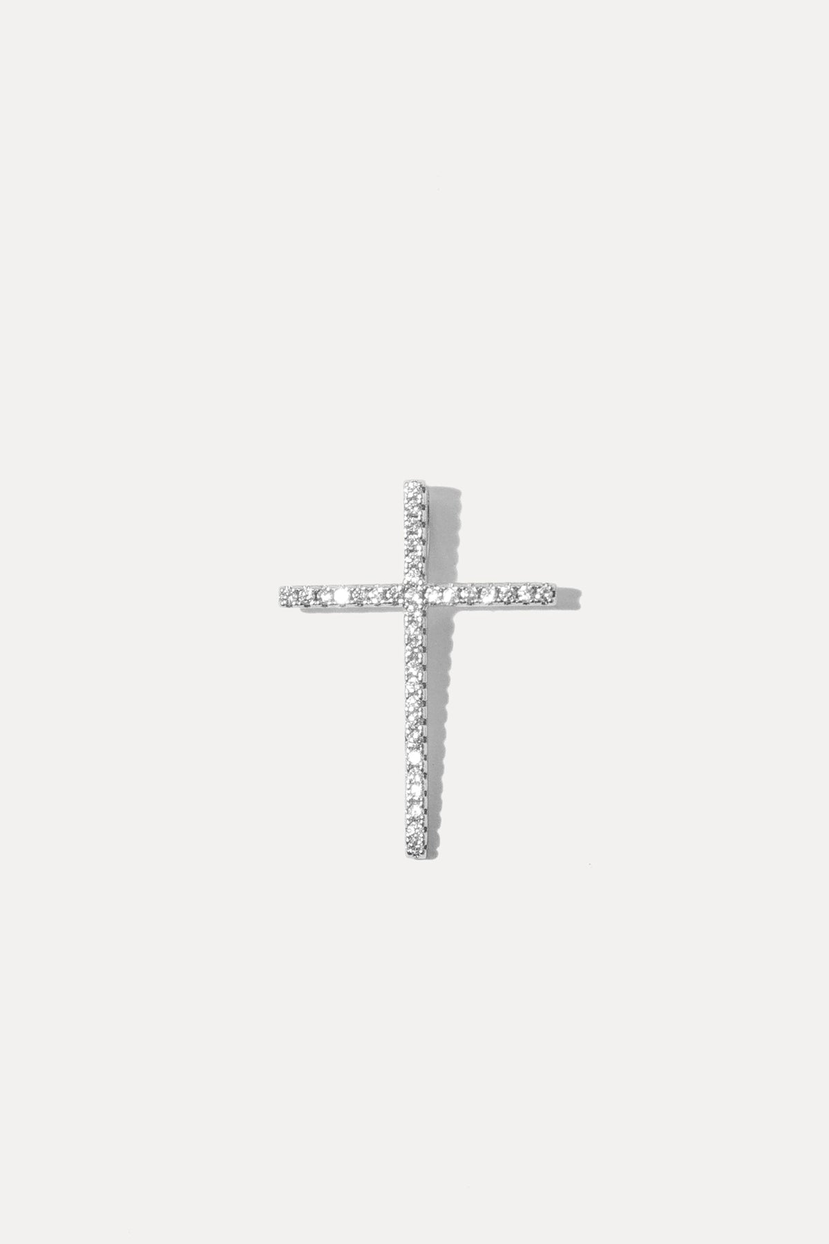 Silver cross charm set with sparkling clear cubic zirconia stones on a bail against a plain white background.