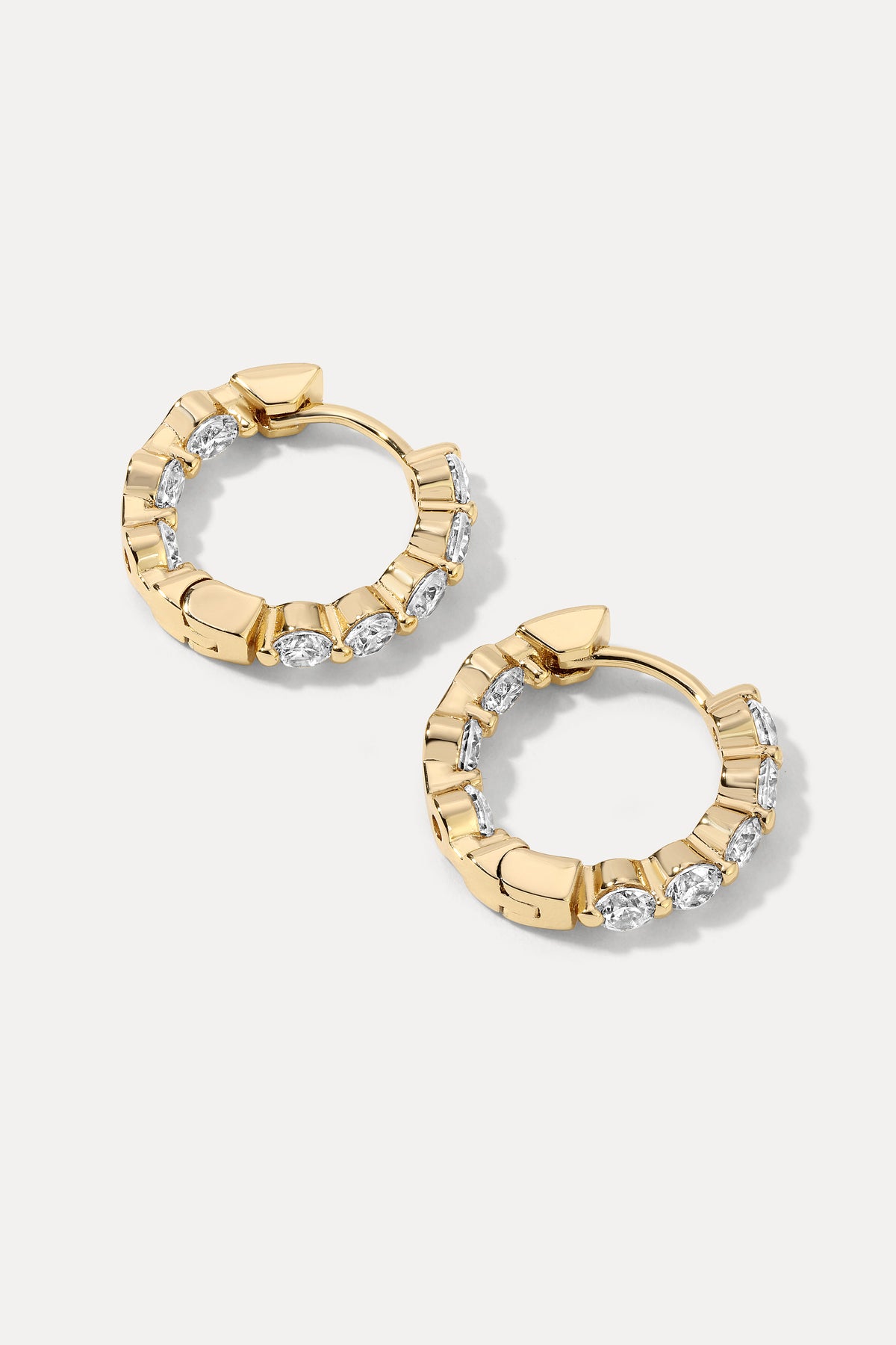 Pair of gold Shea Hoops with embedded cubic zirconia stones flat lay on a white background.