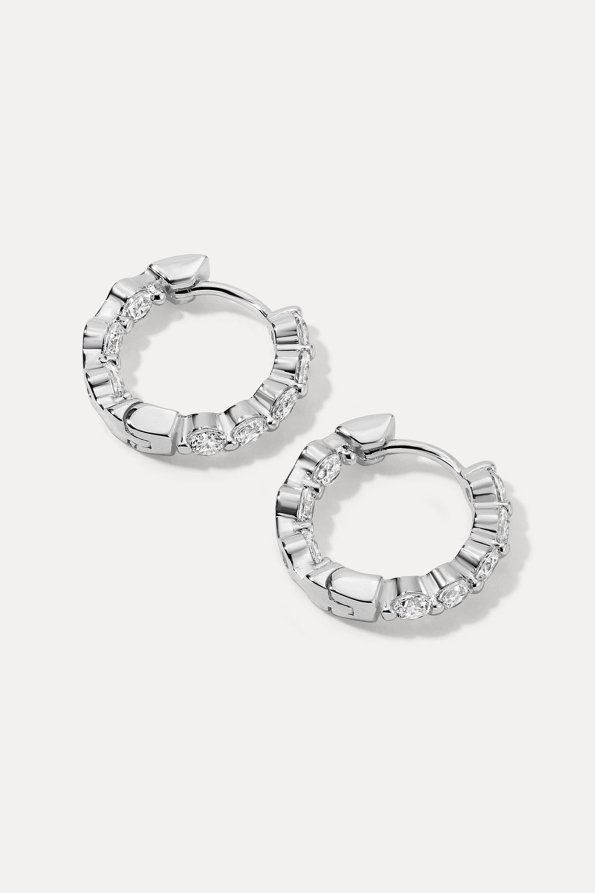 Pair of silver Shea Hoops with embedded cubic zirconia stones flat lay on a white background.
