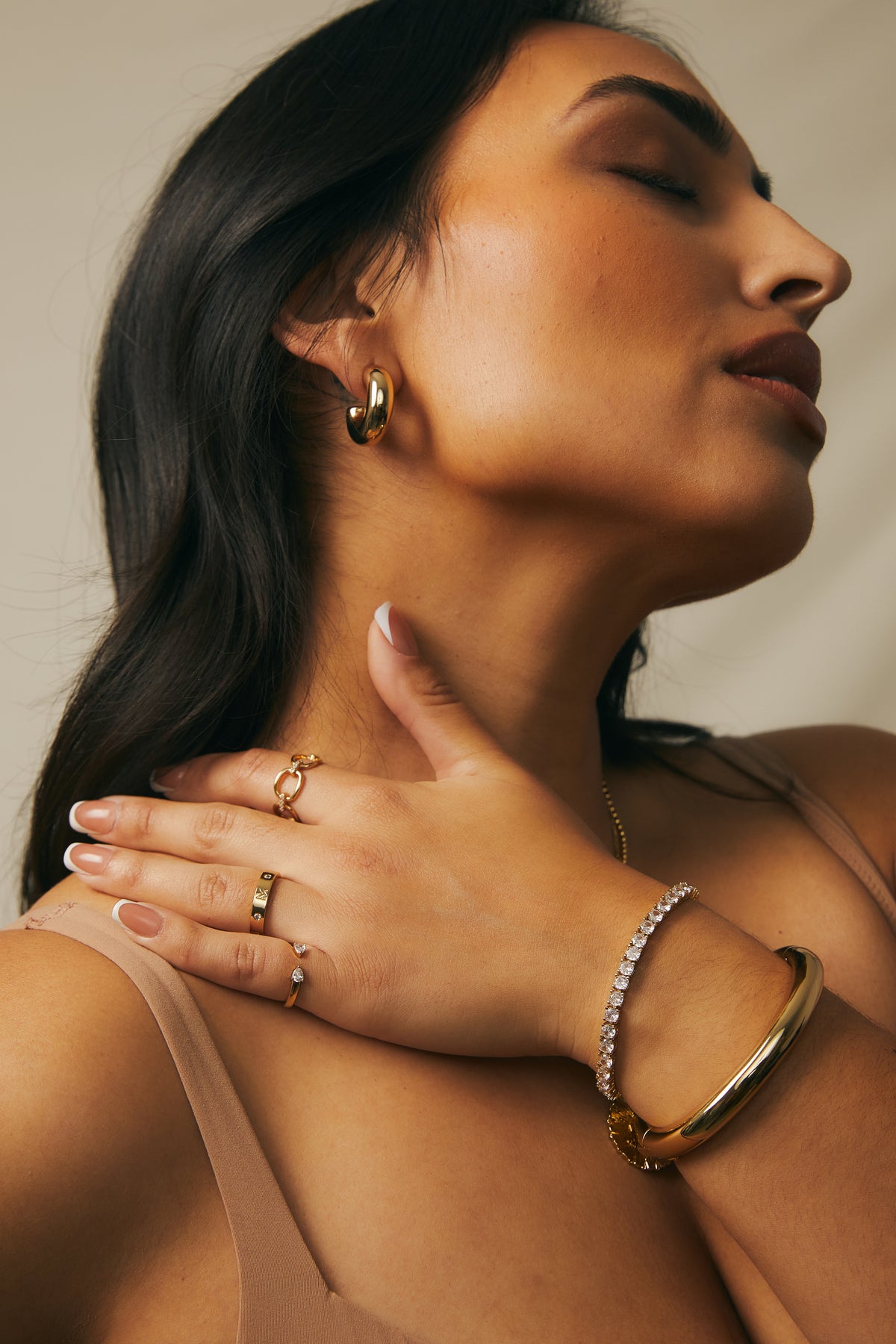 Model wearing the gold Audrey bracelet and gold Cleo cuff with various rings.