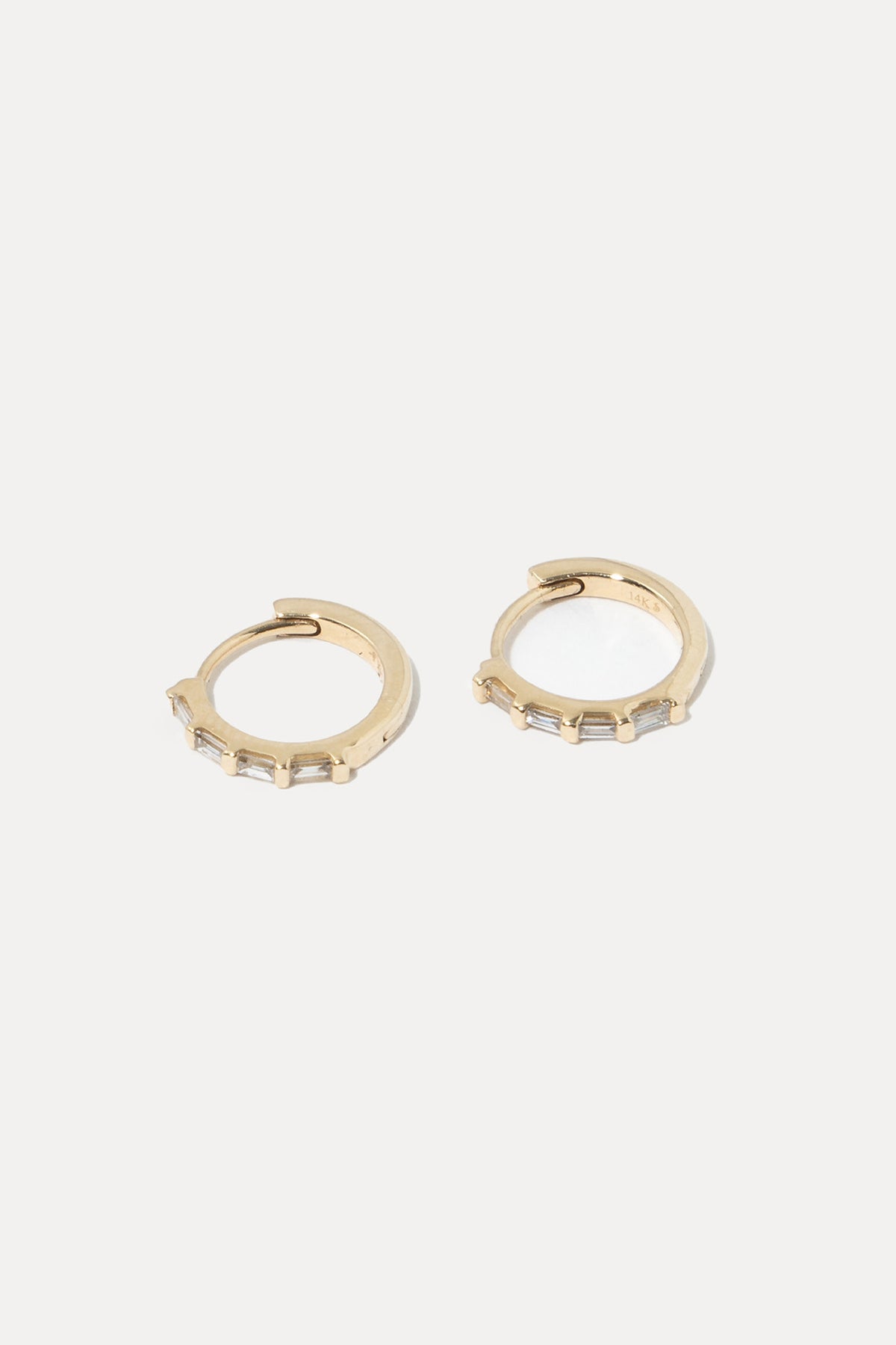 Pair of 14K gold baguette diamond huggie hoop earrings displayed on a plain white background.