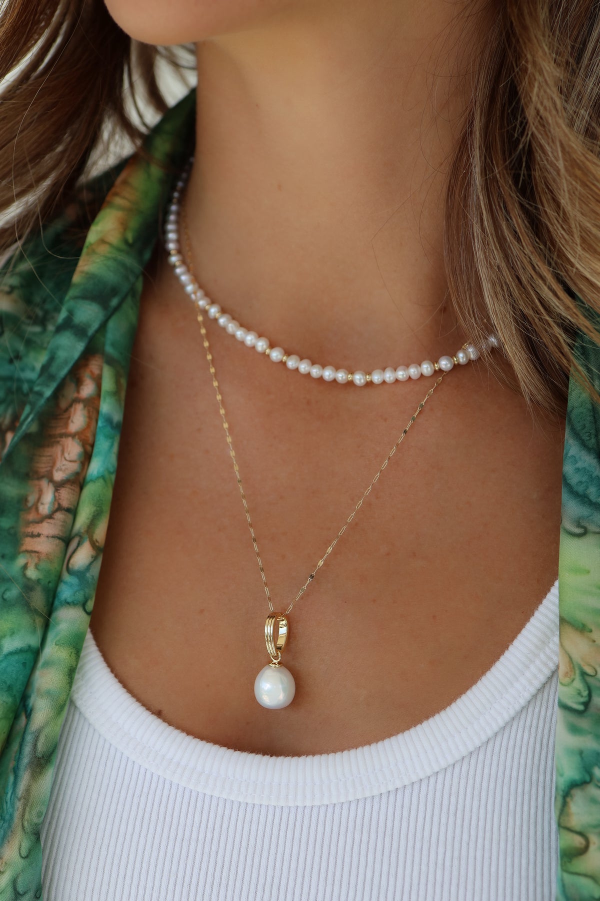 Close up model image of the Bette necklace in gold paired with the Perla pearl charm.