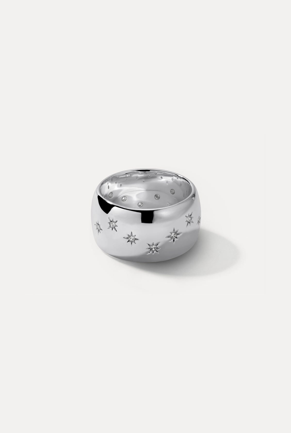 Silver Celeste wide cigar band ring featuring engraved starburst settings with CZ stones on a white backdrop.