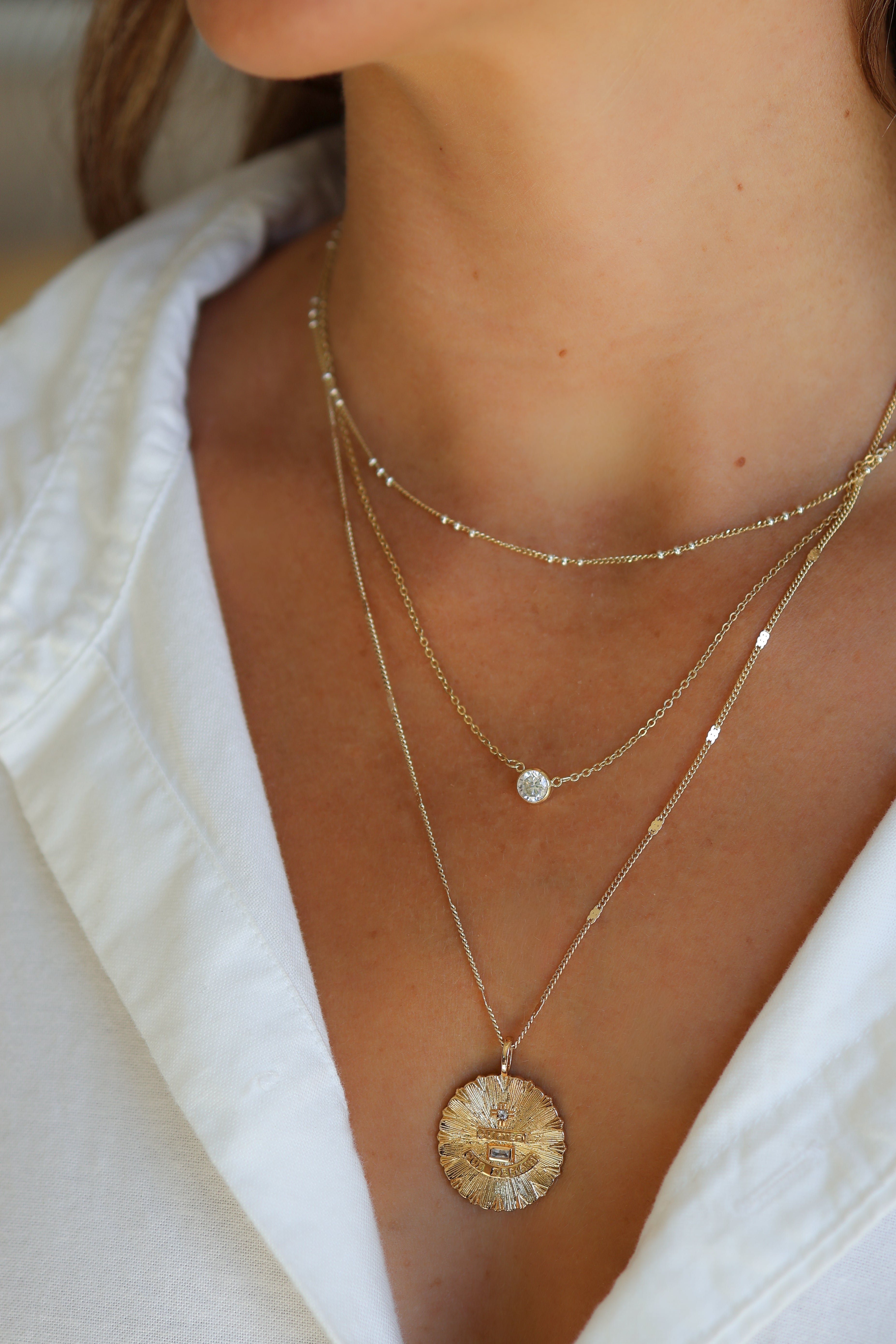 Model wearing the gold Coco cable chain necklace styled with the gold love charm and layered with the stephanie necklace