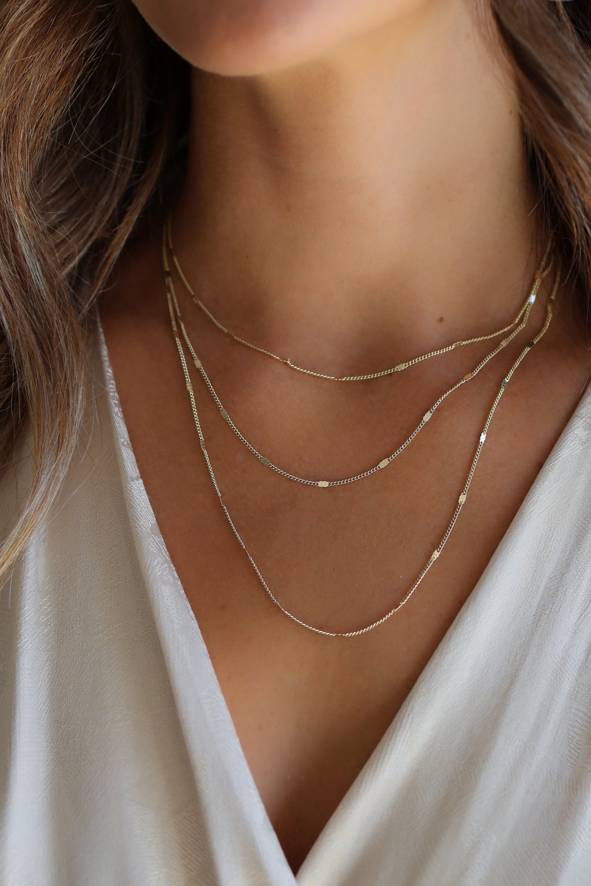 Model wearing the gold Coco chain necklace layered in three distinct sizes.