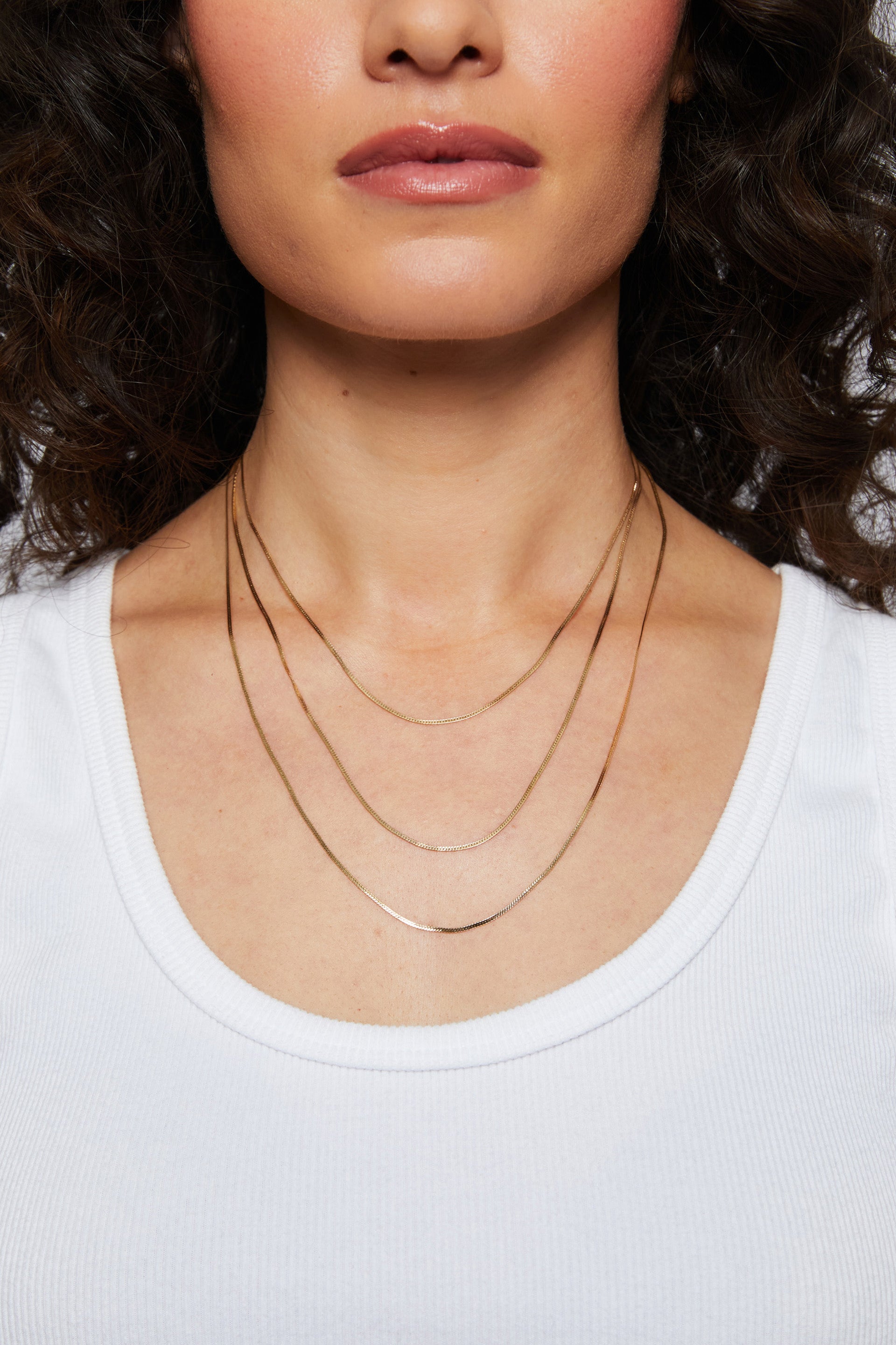 Model wearing a ribbed top showcasing the sleek gold Josephine Chain herringbone necklace in three sizes.