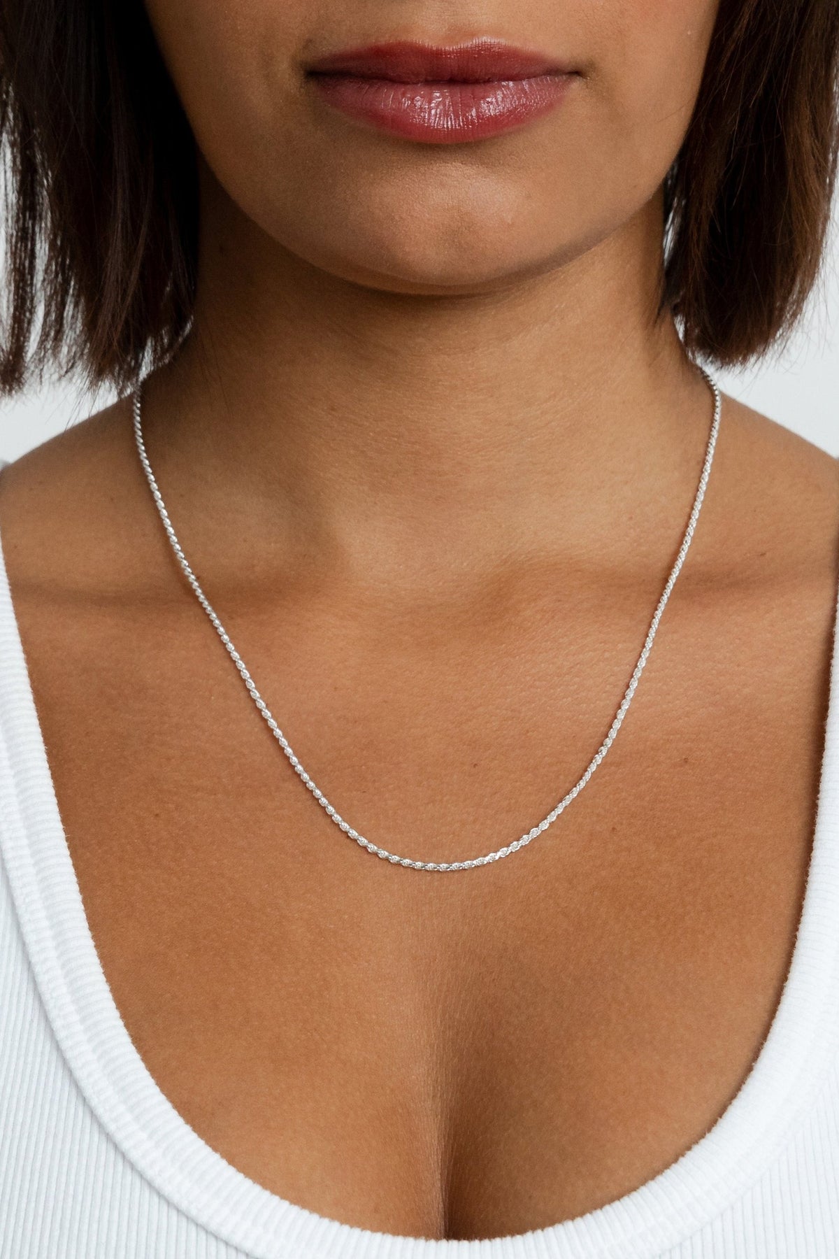 Model showcasing the silver Kate Chain rope necklace resting lower on her neckline.