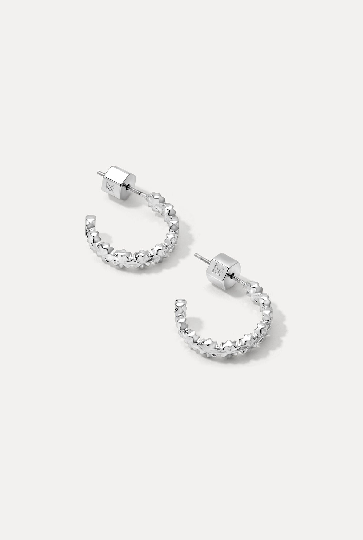 Pair of silver Lauren Hoops with starburst-inspired pattern on a clean white background.