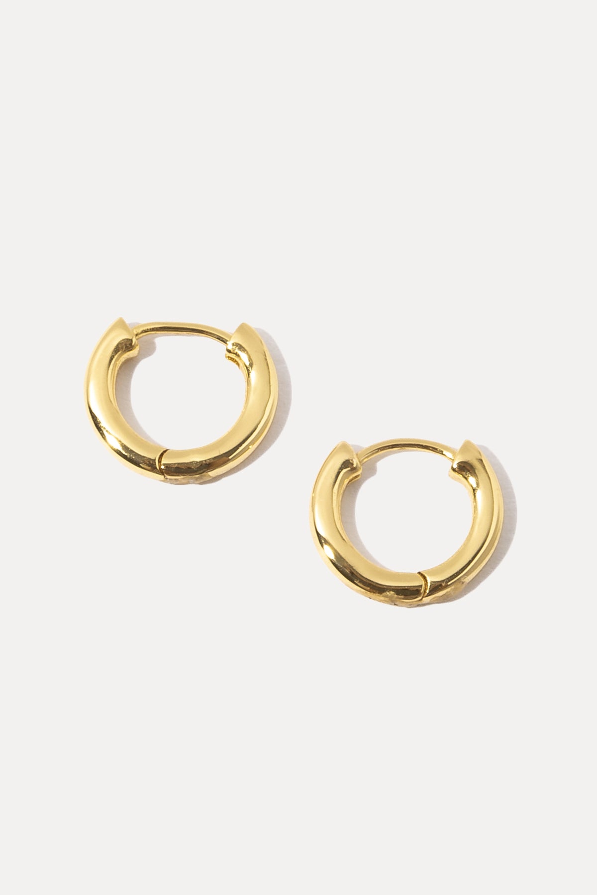 Pair of gold Maxwell Huggies featuring a smooth, classic hoop design on white background.