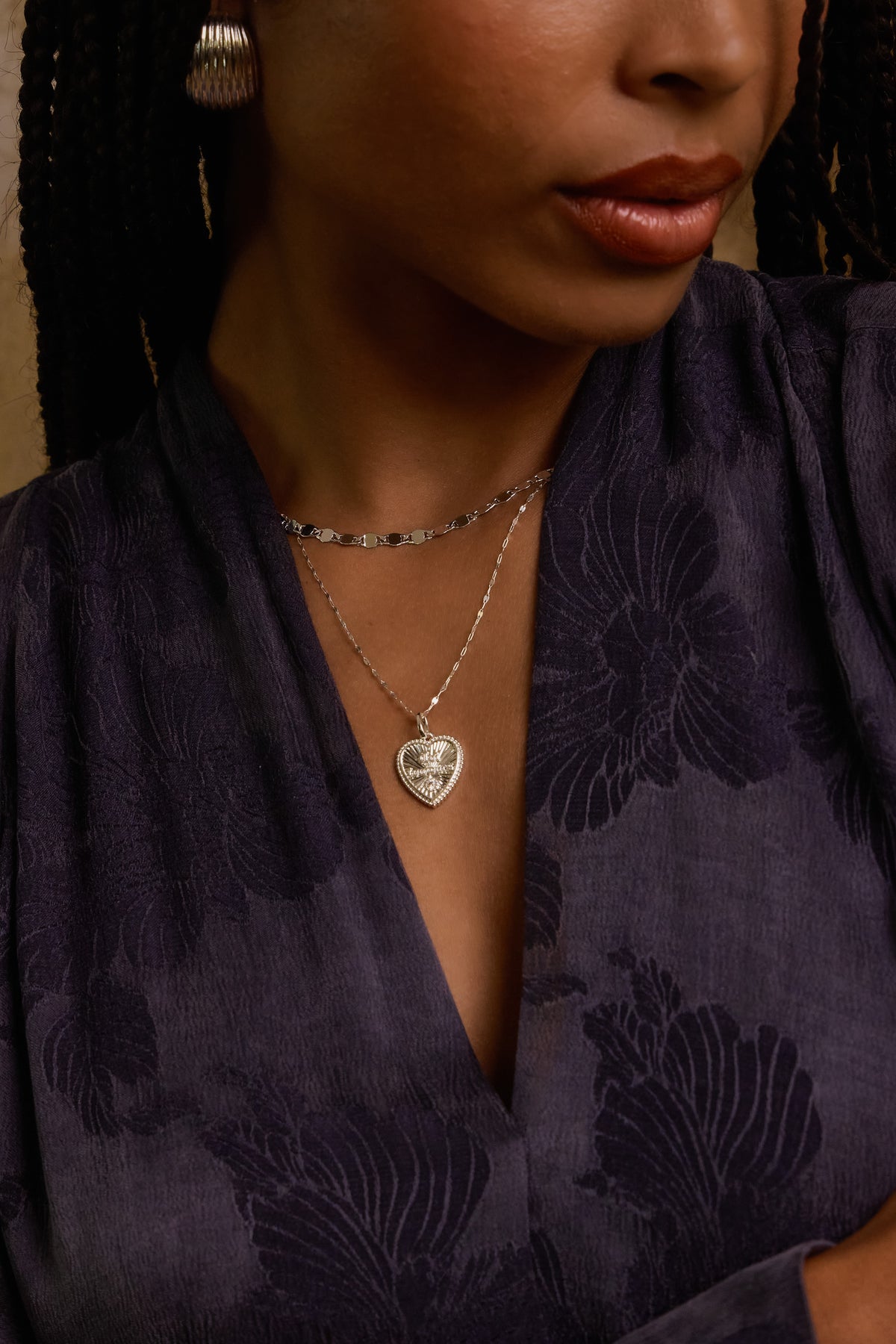 Model wearing silver Forever Charm on nora chain layered with Ava mirror chain, styled in a dark floral jacquard wrap top.