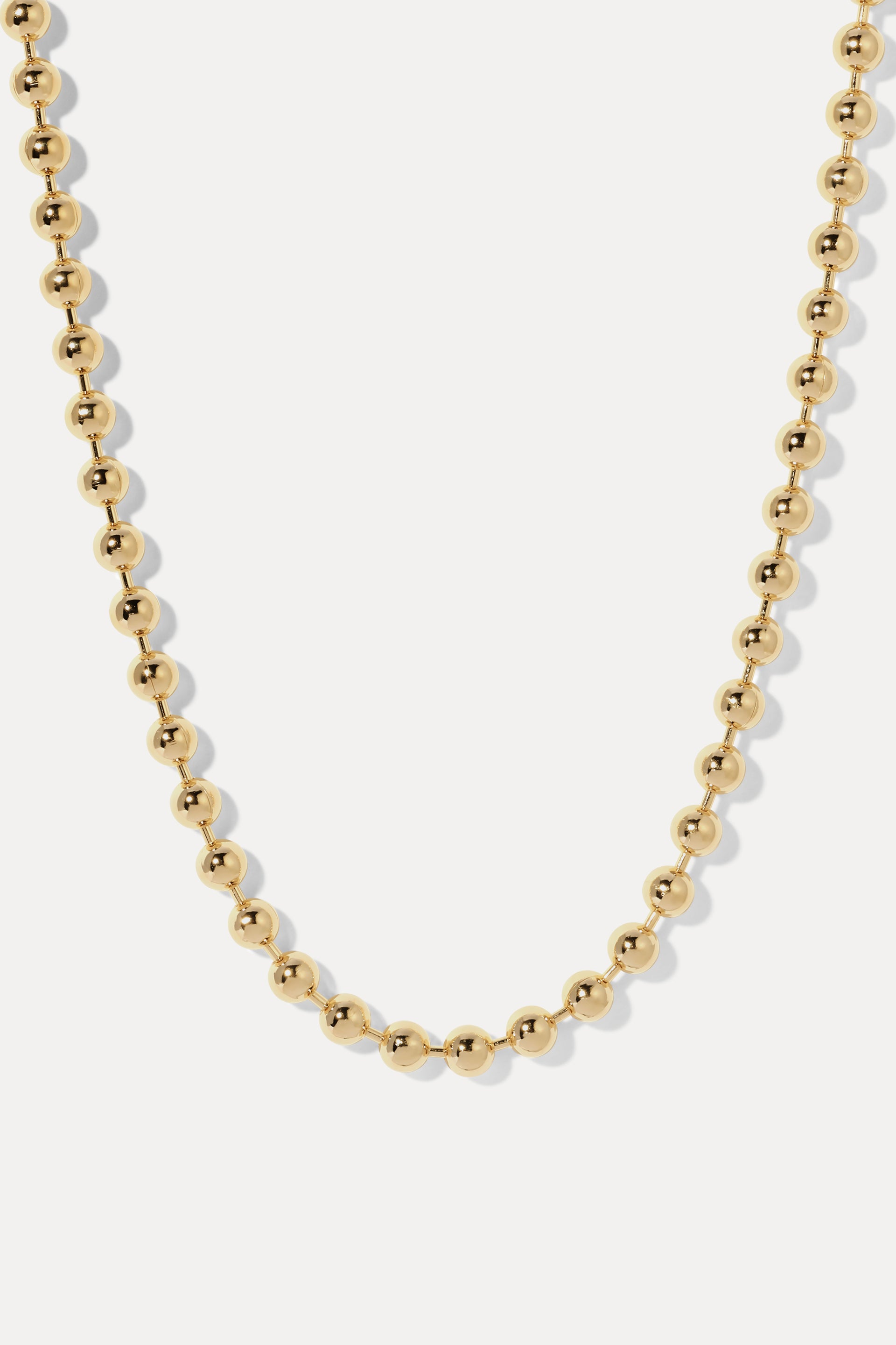 Amelia Gold Ball Chain Necklace draped in a loop on a white background, highlighting the polished gold beads.