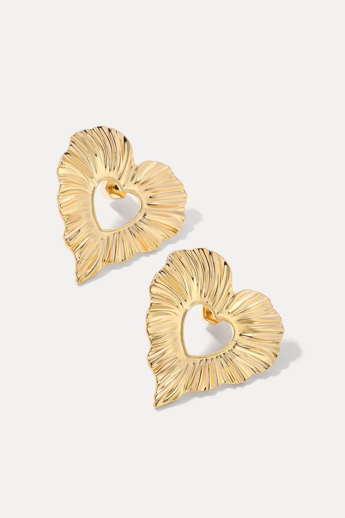 A pair of gold heart-shaped stud earrings with a textured outer edge and a hollow center, displayed on a light gray background.