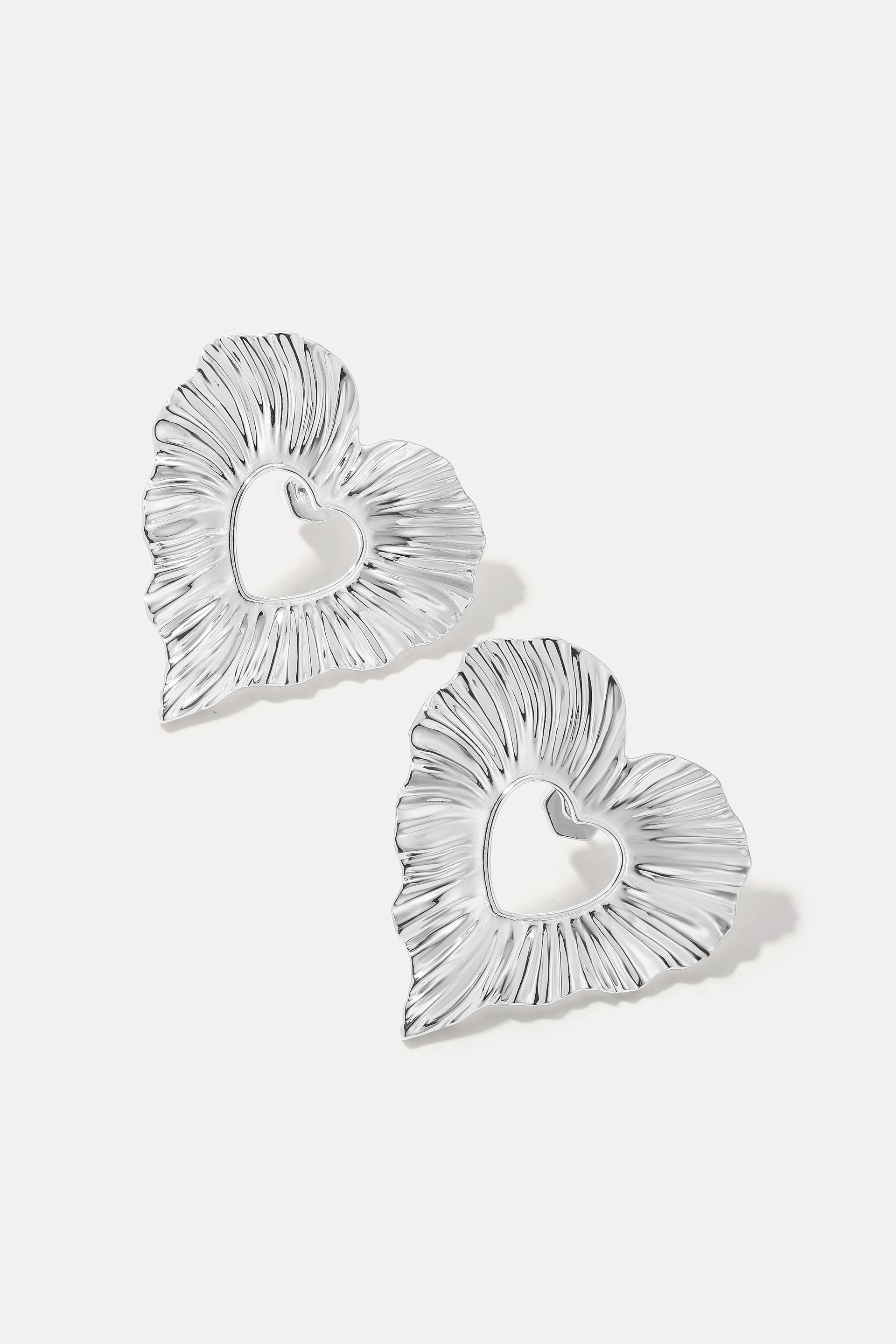 Pair of silver Amour textured heart statement earrings on a white background.