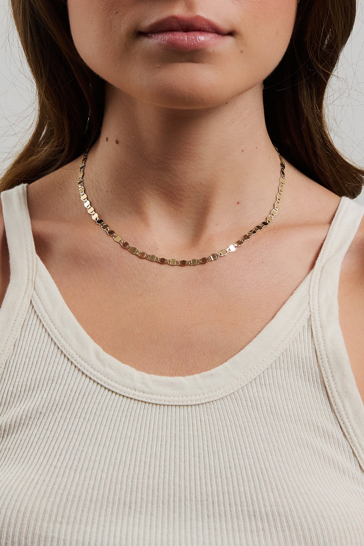 Gold mirror chain necklace styled on a model wearing a ribbed tank