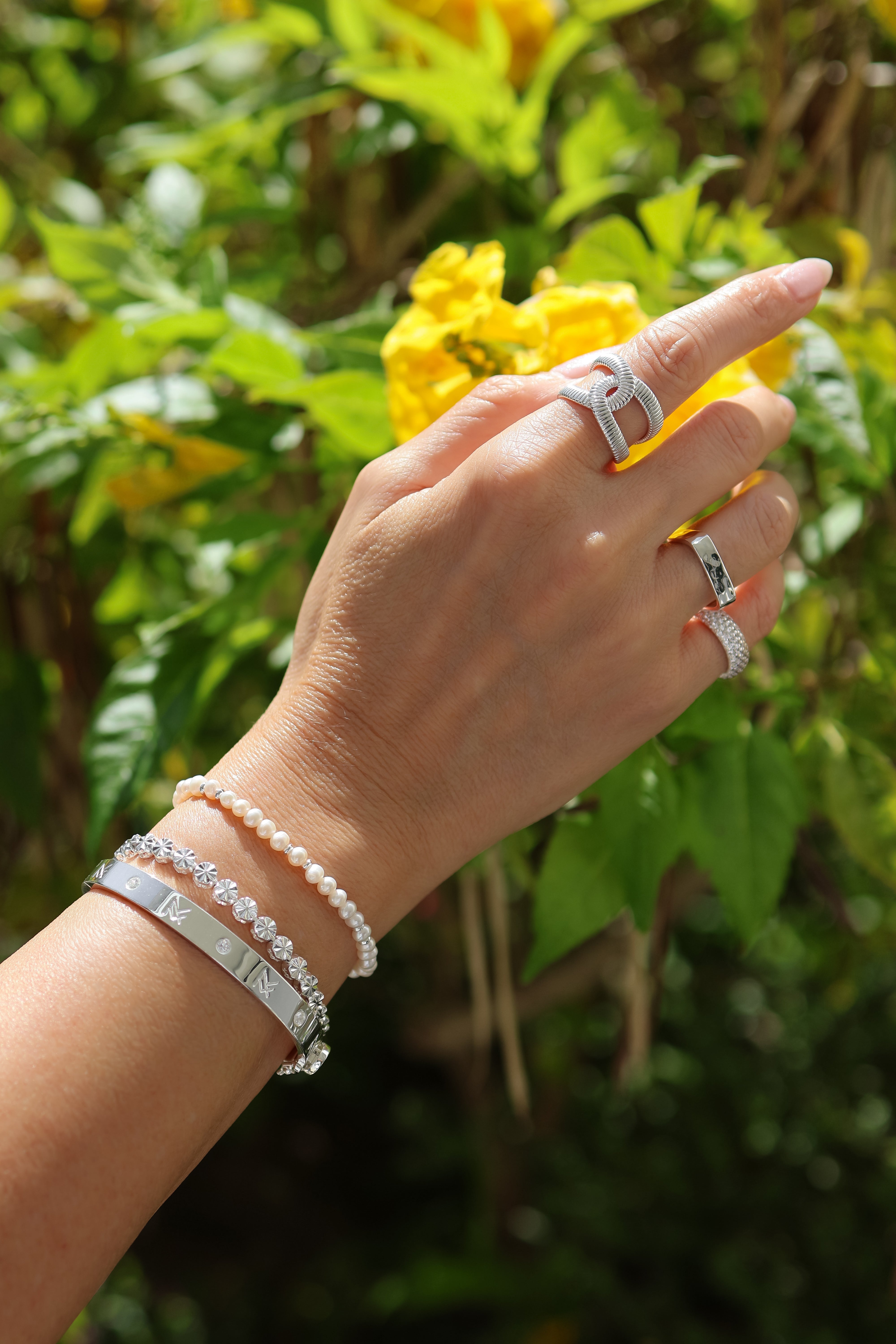 Model's hand displaying the silver Bette bracelt and MF cuff paired with silver rings.