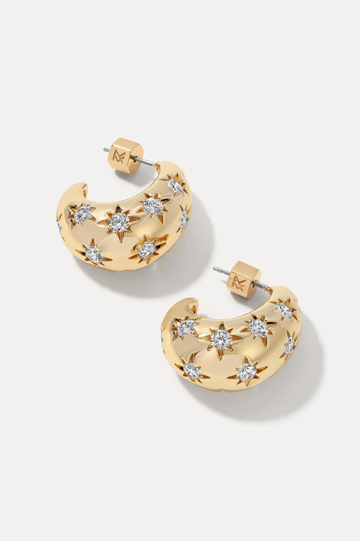 Gold chunky hoop earrings engraved with starburst clear cubic zirconia gems.