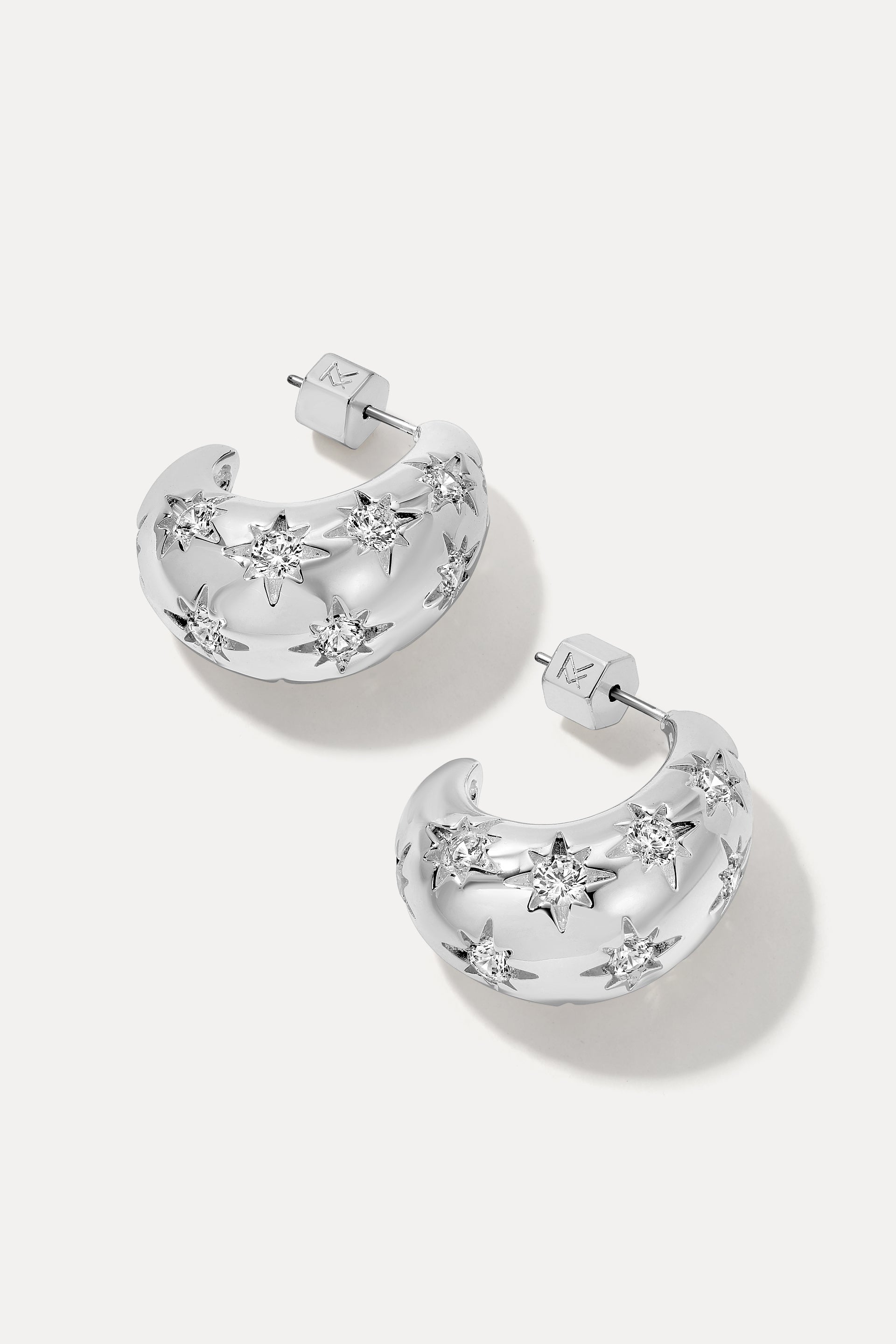 The Celeste Silver chunky hoop earrings engraved with starburst clear cubic zirconia gems.