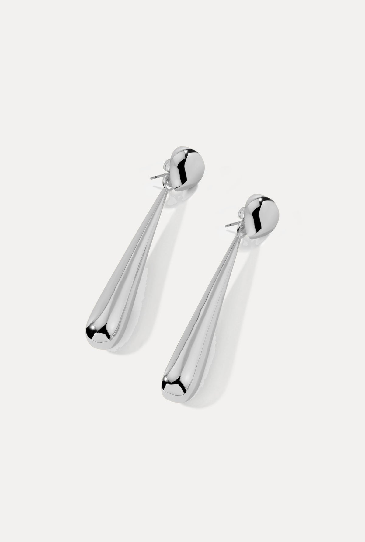 Silver teardrop Claudette earrings with fluid drop design on a white background.