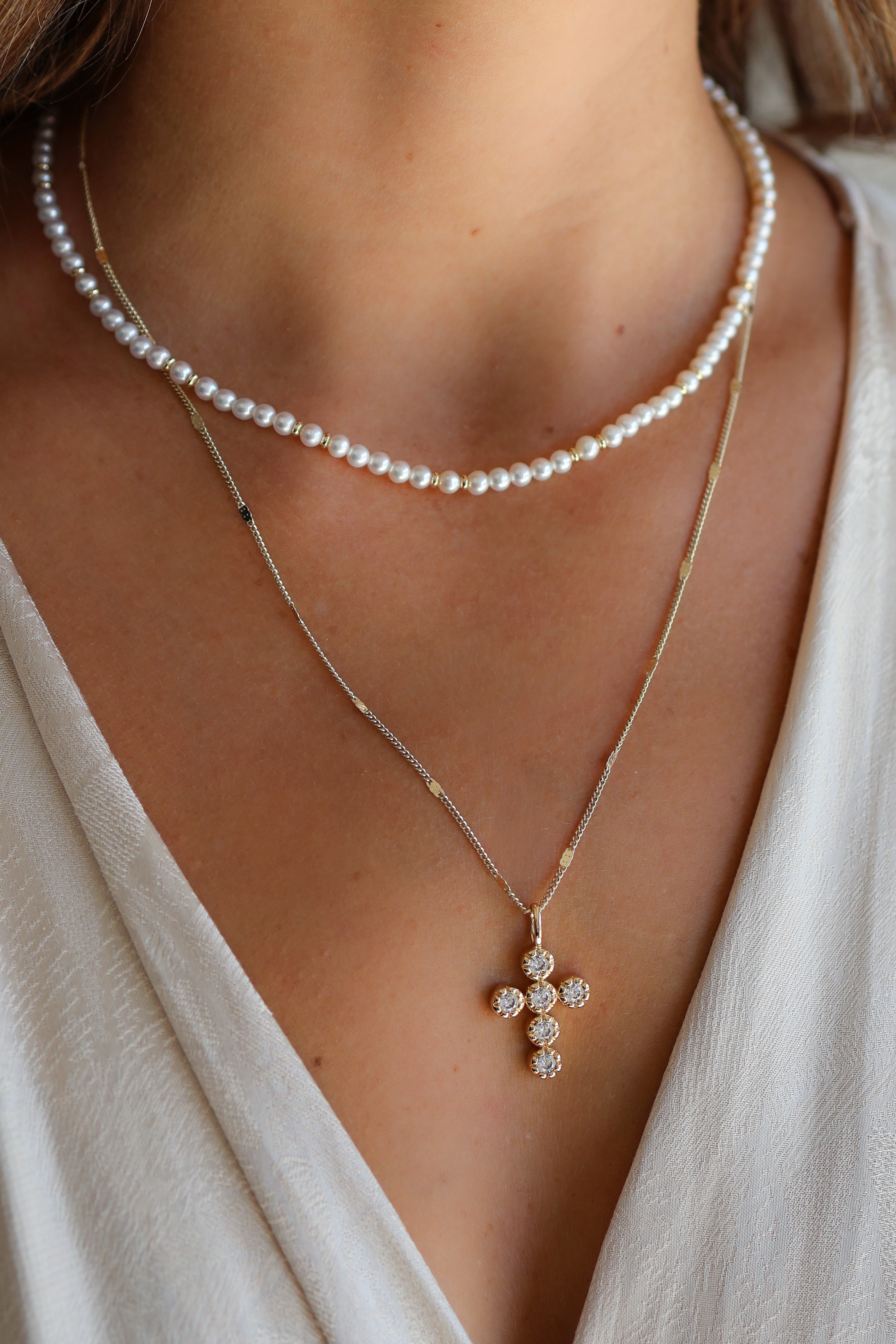 Close-up of a model wearing the gold Coco cable chain and eternal charm with the bette necklace in gold.
