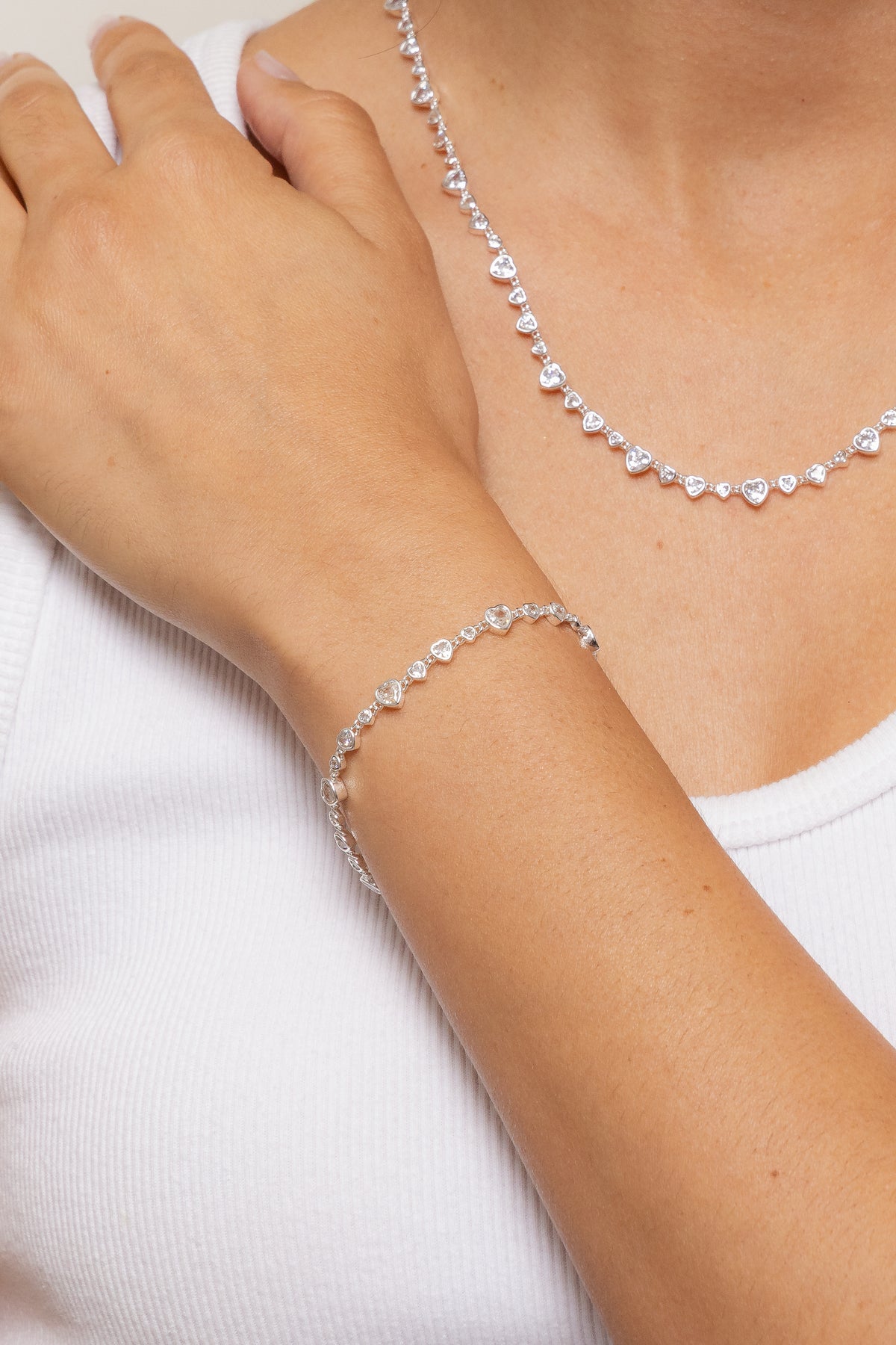 Model wearing the silver Cora bracelet paired with the silver Cora necklace agains a white blouse.