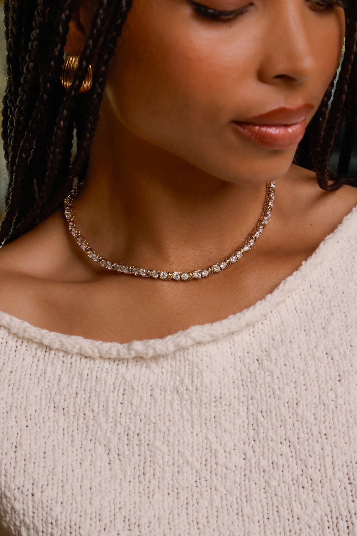 Model wearing gold Delilah tennis necklace with sparkling CZ stones, styled with a cream textured knit top.
