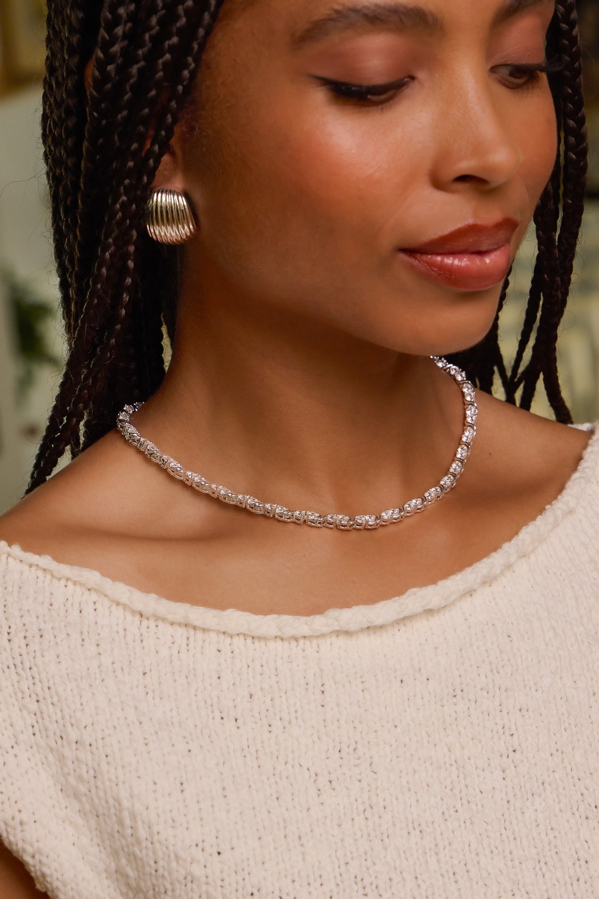 Model wearing silver Delilah tennis necklace with CZ stones and Florence dome earring styled in a cream knit top.