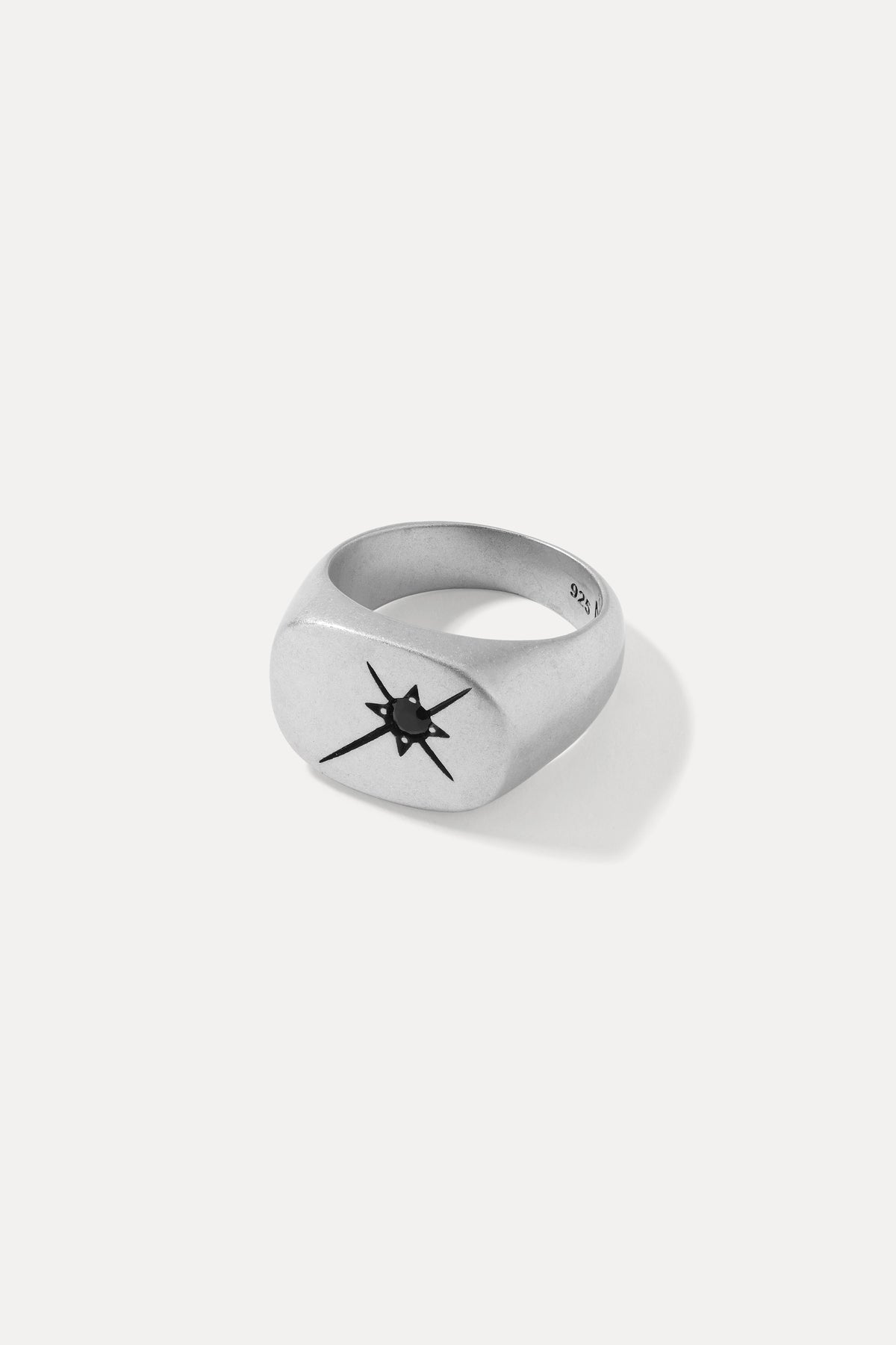 Studio product shot of the silver Dean signet ring with a starburst-set black gem, on a white background.