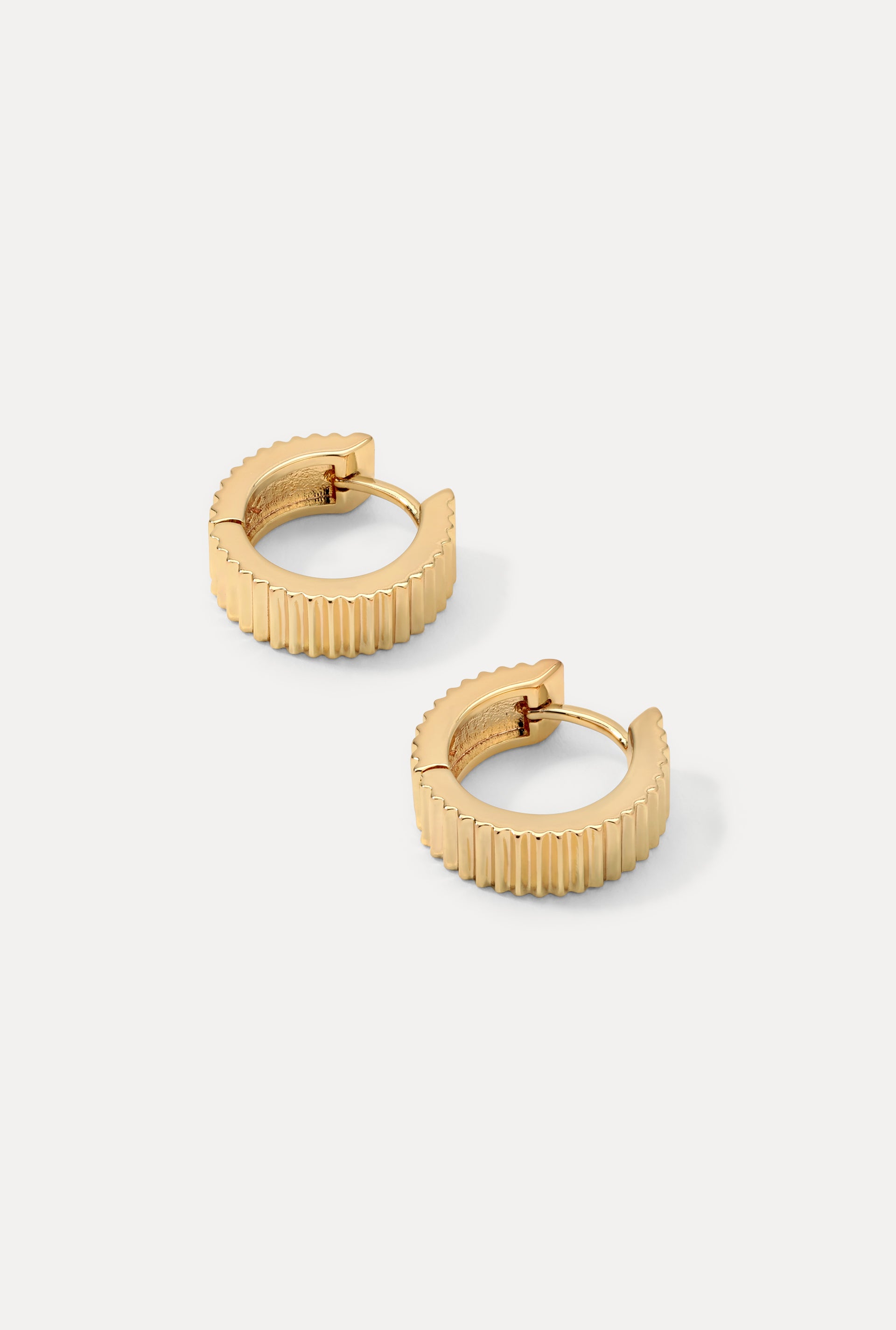Gold Debbie huggie hoop earrings with bold ridged texture on a plain white background.