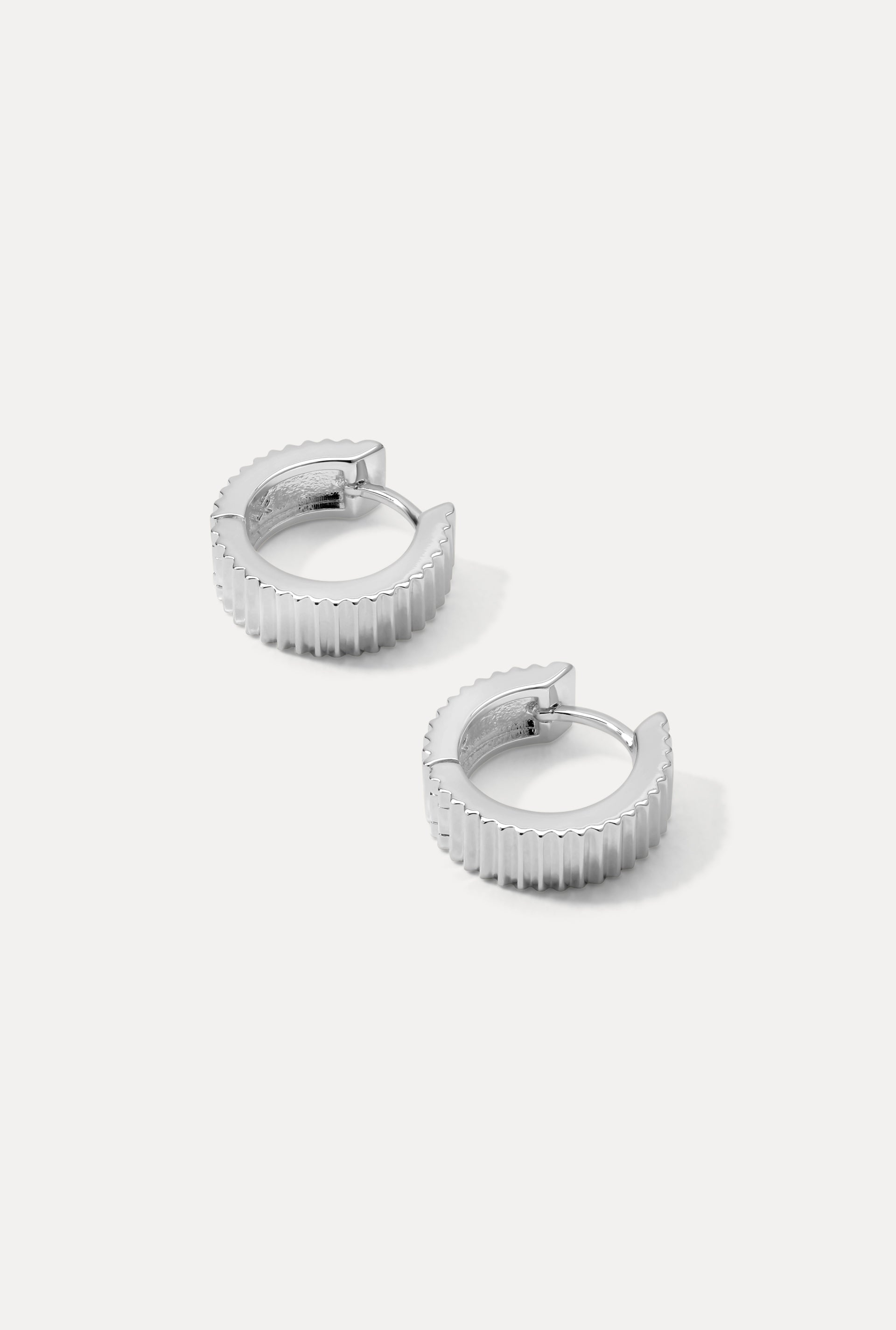 Silver Debbie huggie hoop earrings with bold ridged texture on a plain white background.