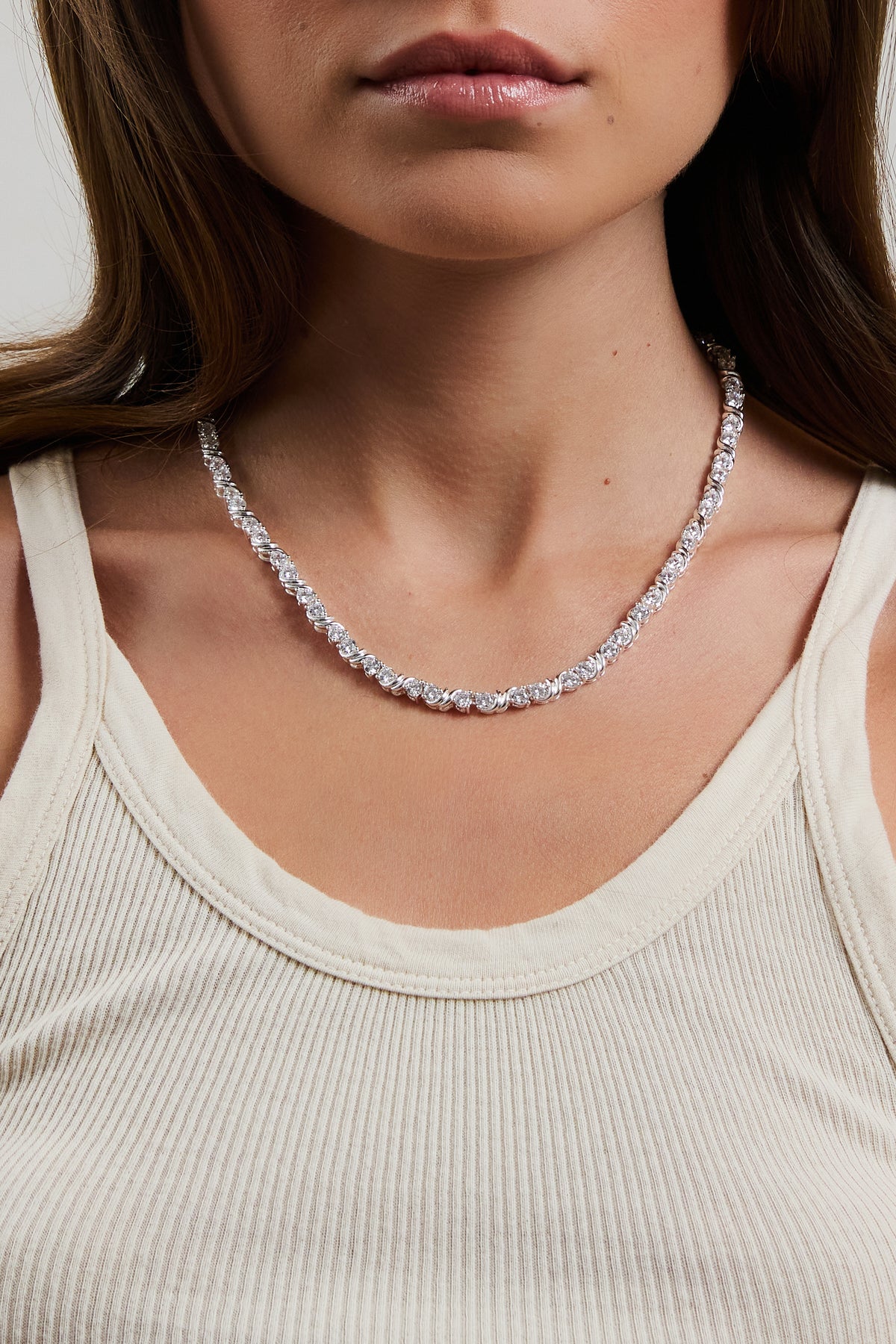 Model wearing silver Delilah tennis necklace with CZ stones, styled with a cream ribbed tank.