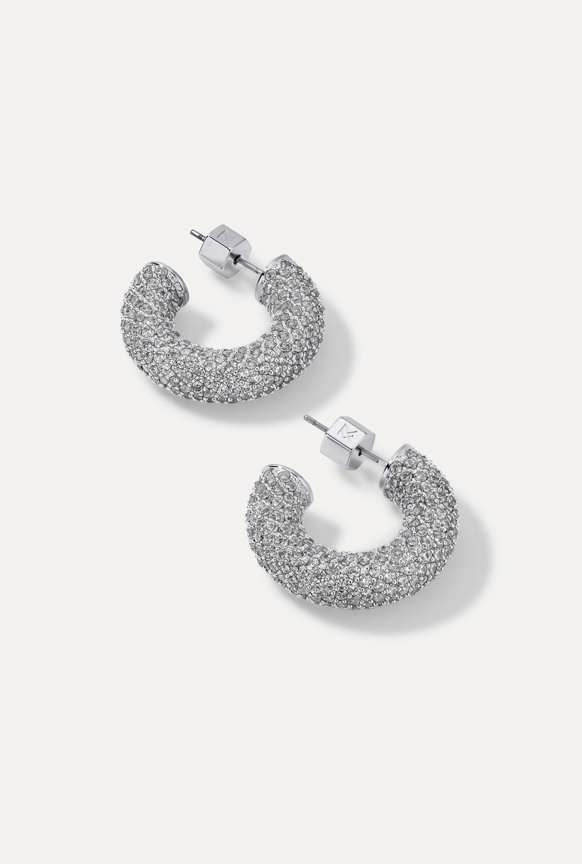 Silver thick rounded hoop earrings with full cubic zirconia pavé detailing on a plain white background.