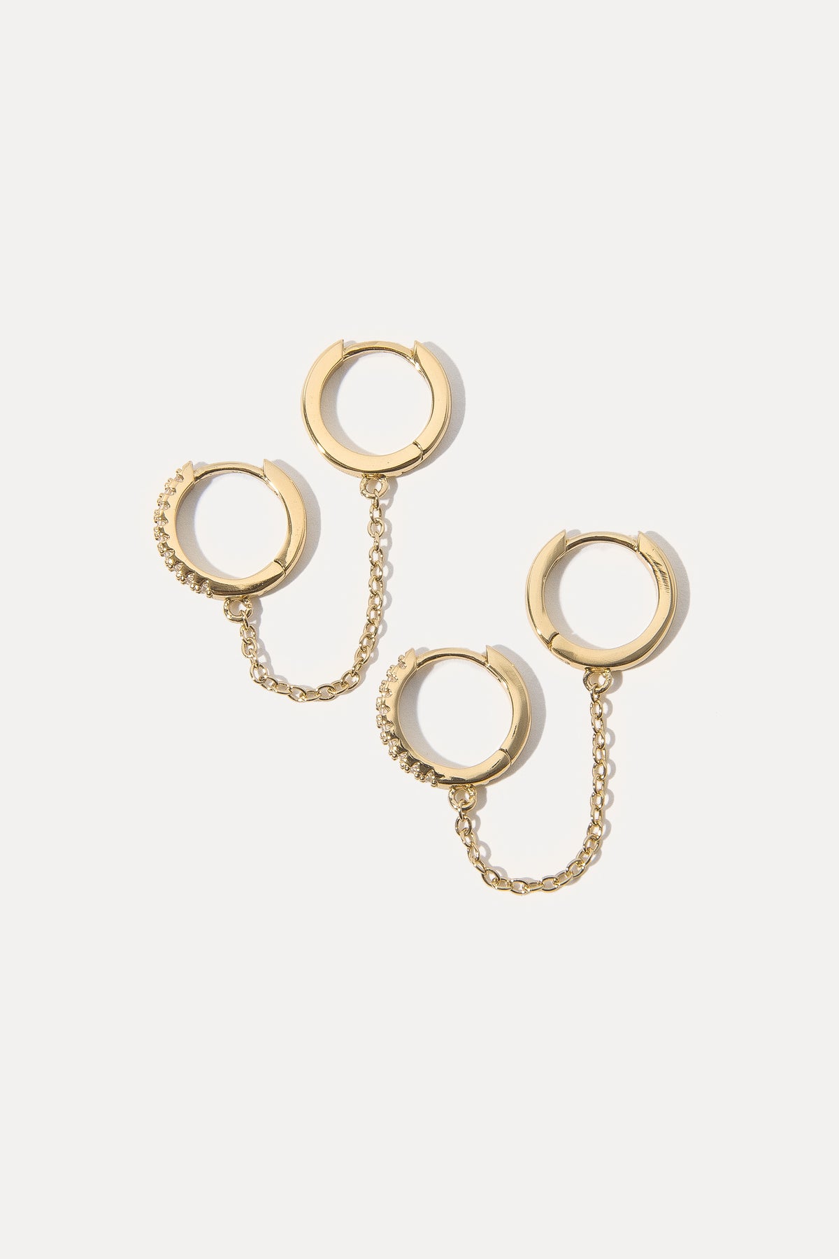 Gold double hoop earrings linked by a chain against a clean white background.