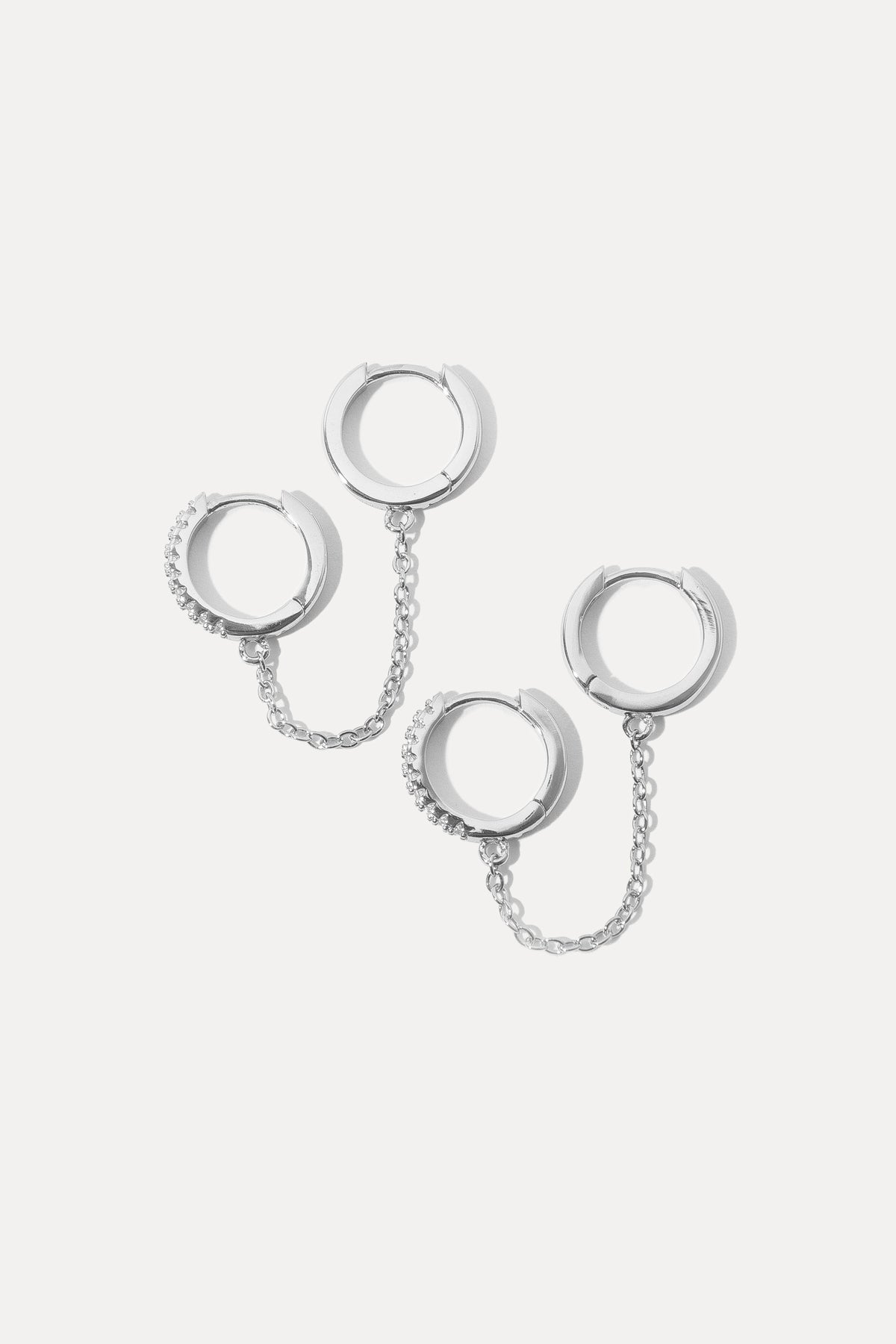 Silver double hoop earrings linked by a chain against a clean white background.