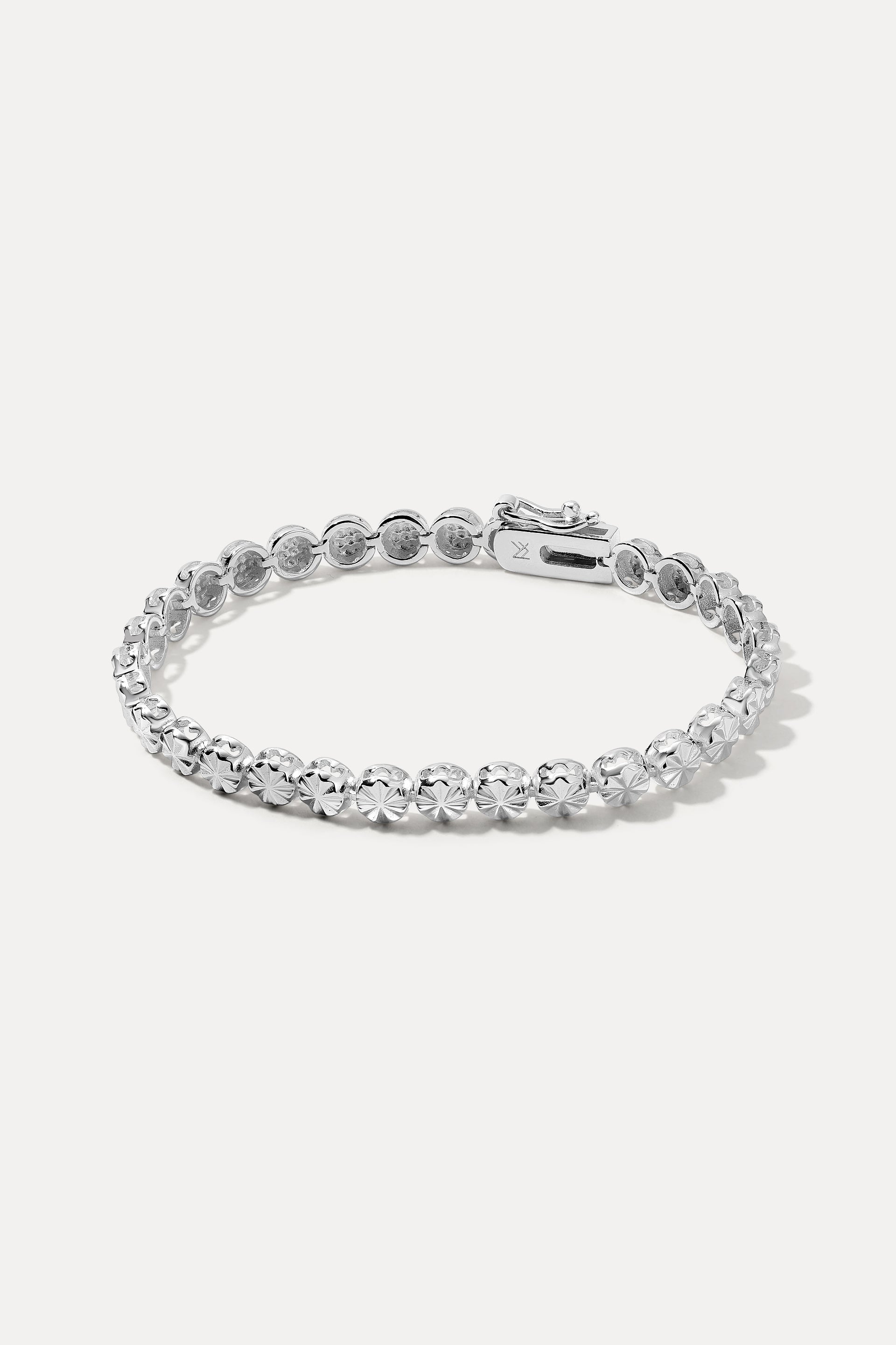 Sterling silver Essie Bracelet displayed in an oval loop on a white background, highlighting its starburst-engraved medallions.